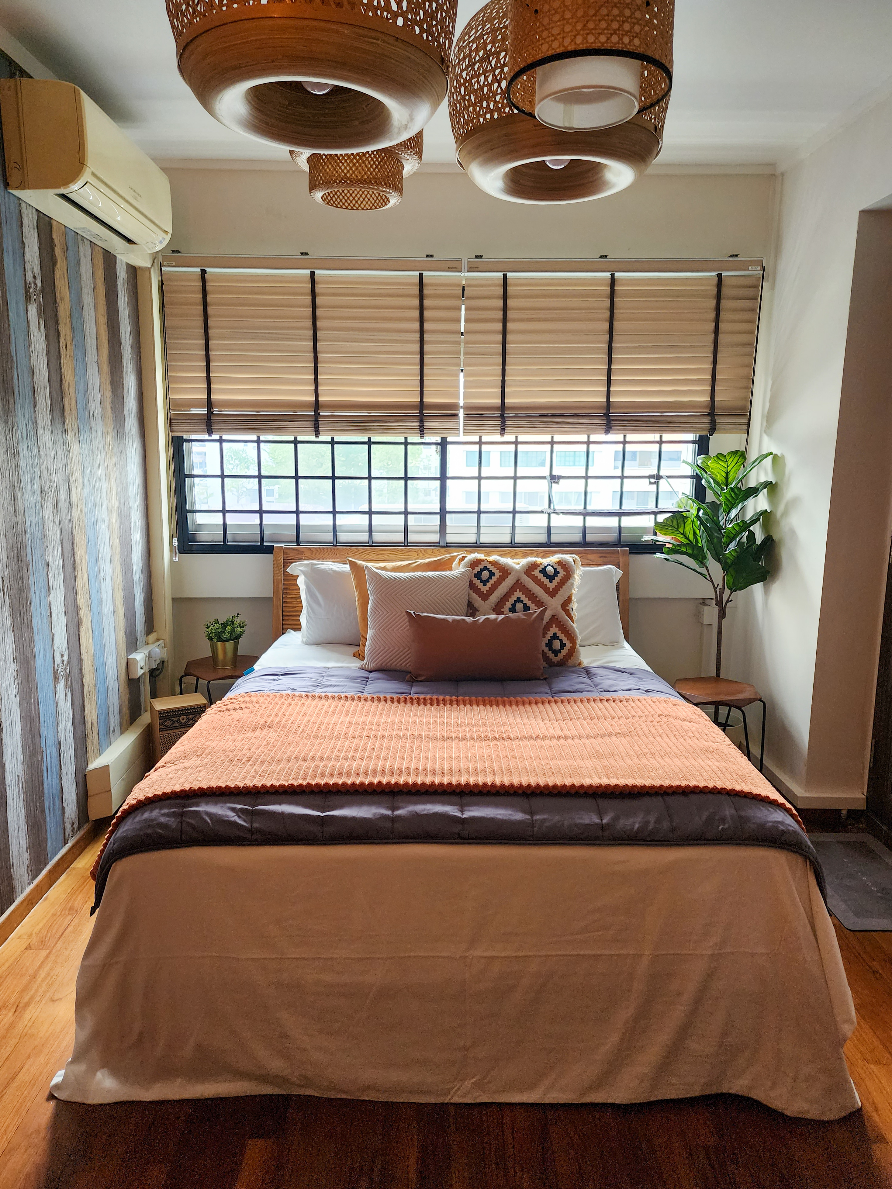 Cosy Escapade - Wooden blinds, modern ceiling light fixture, striped wall, cozy bed, orange blanket, white pillows, geometric