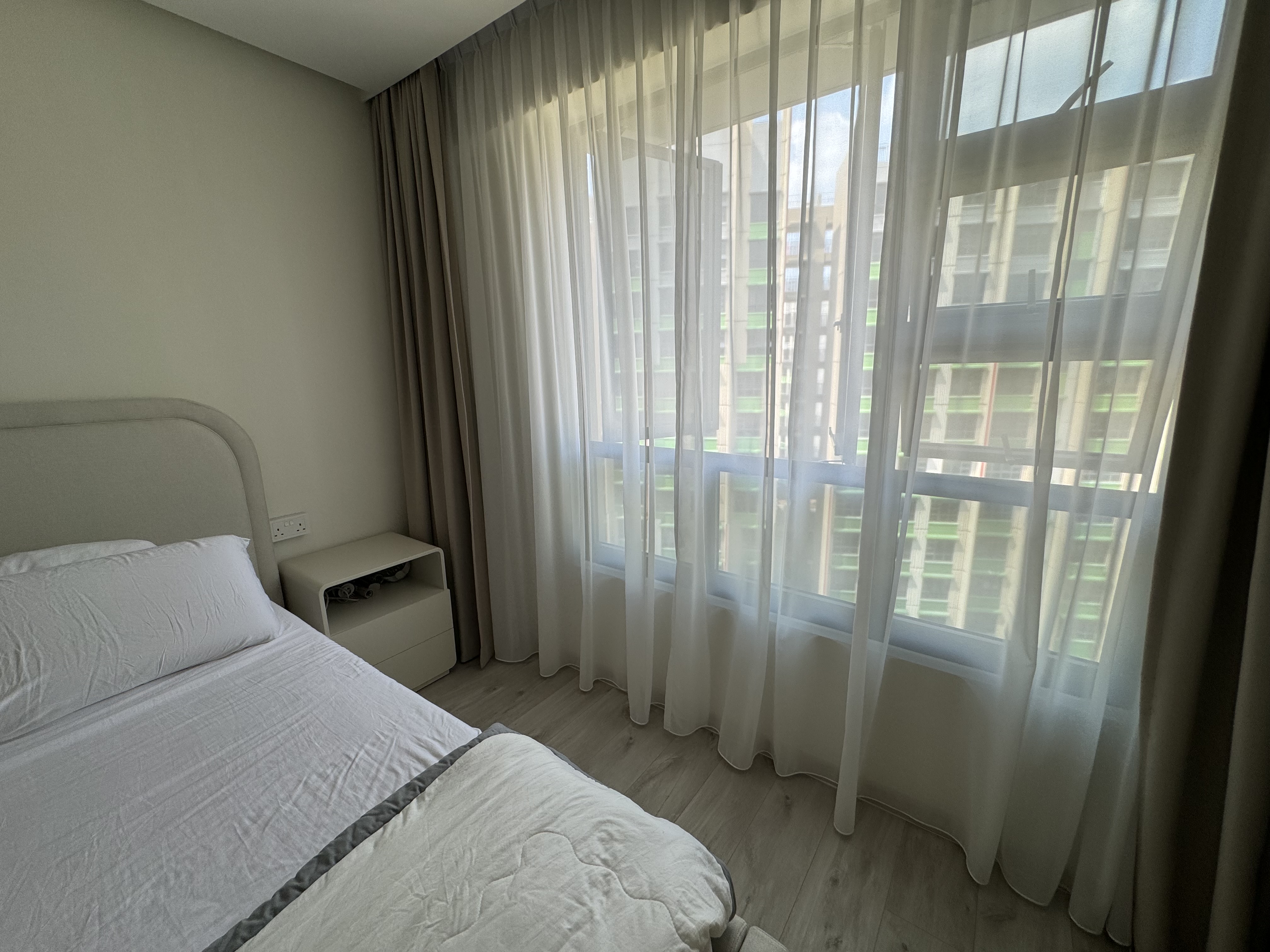 Cozy minimalist bedroom - Modern bedroom with large window, sheer curtains, light-colored walls, neatly made bed with white