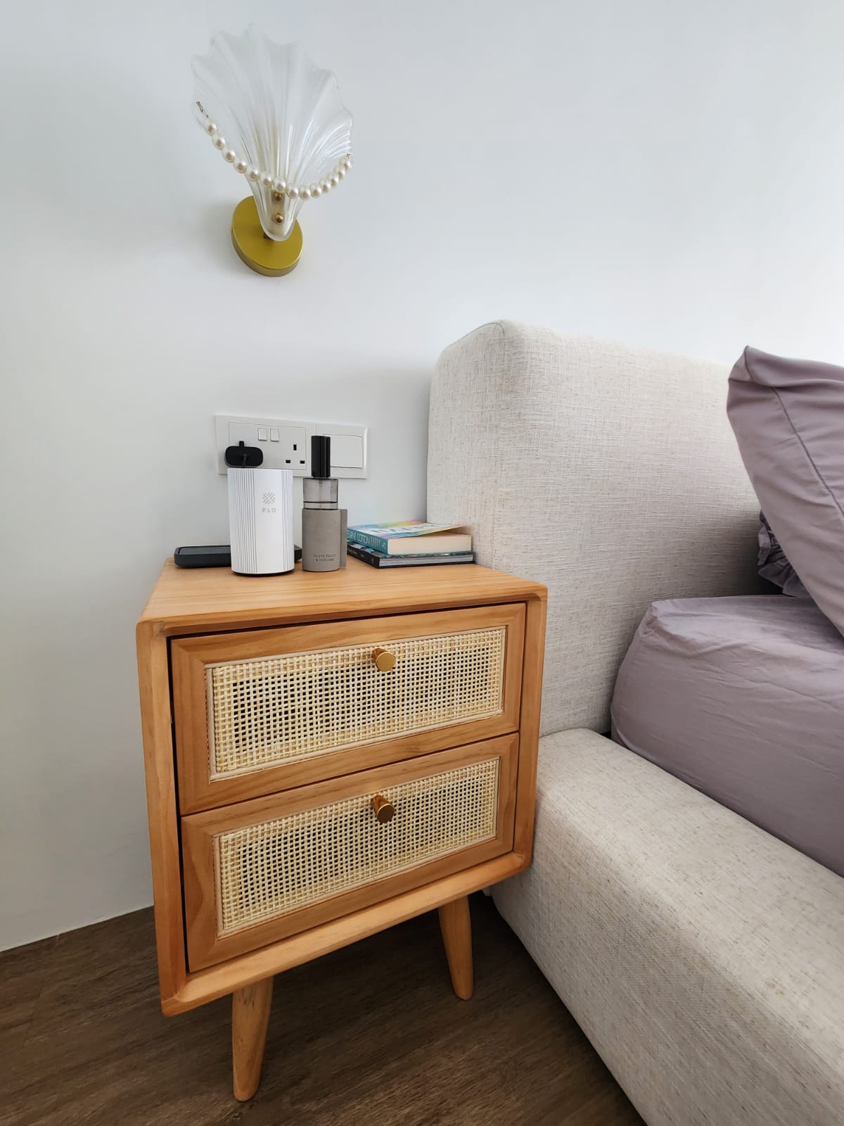 A bedroom with walk-in wardrobe  - Wooden nightstand, beige sofa, white wall, decorative lamp, pearl necklace, books, modern