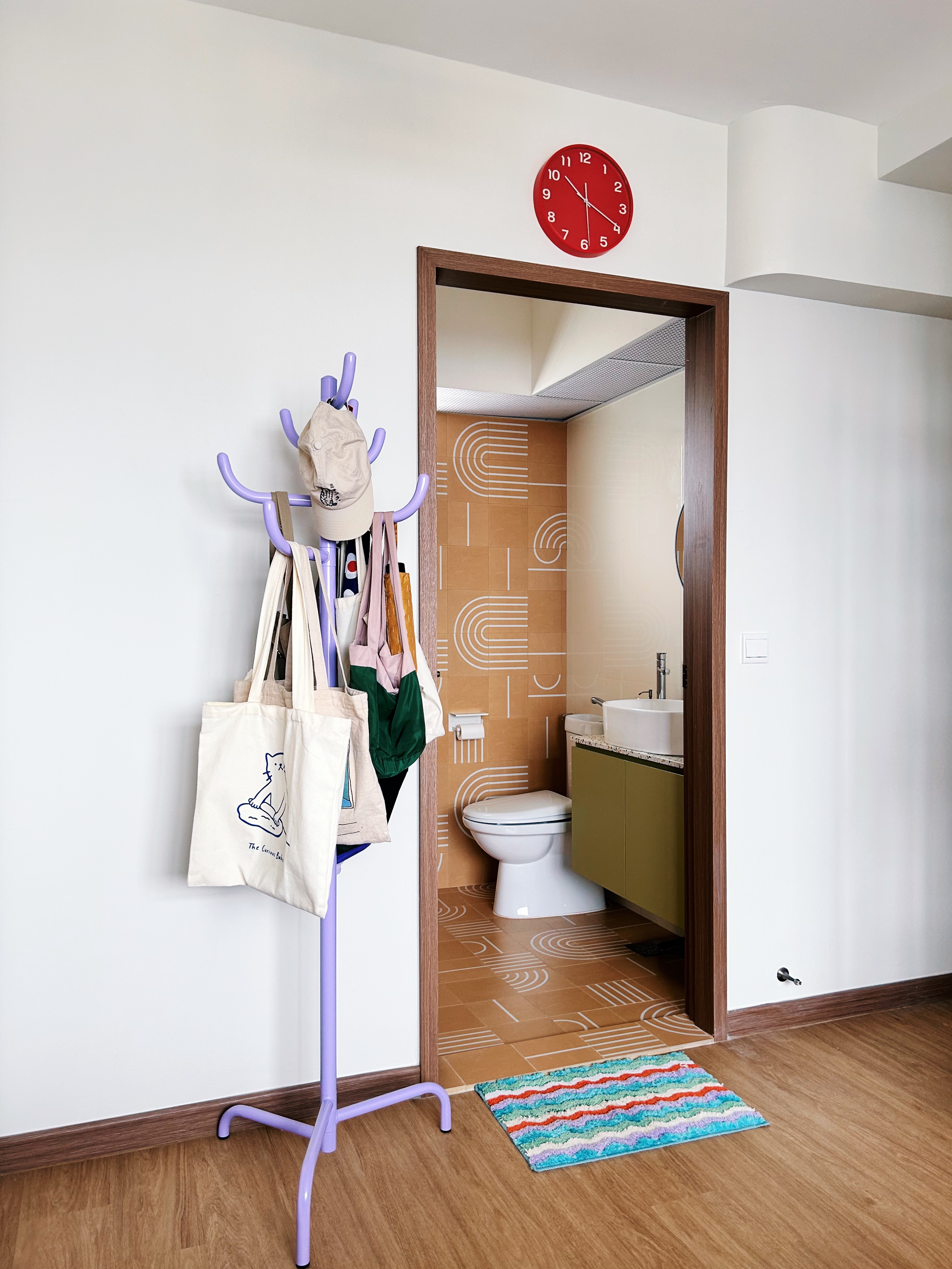 Step into our simple, sleep space - purple rack, beige tote bags, white tote bags, colorful rug, wooden floor, white wall