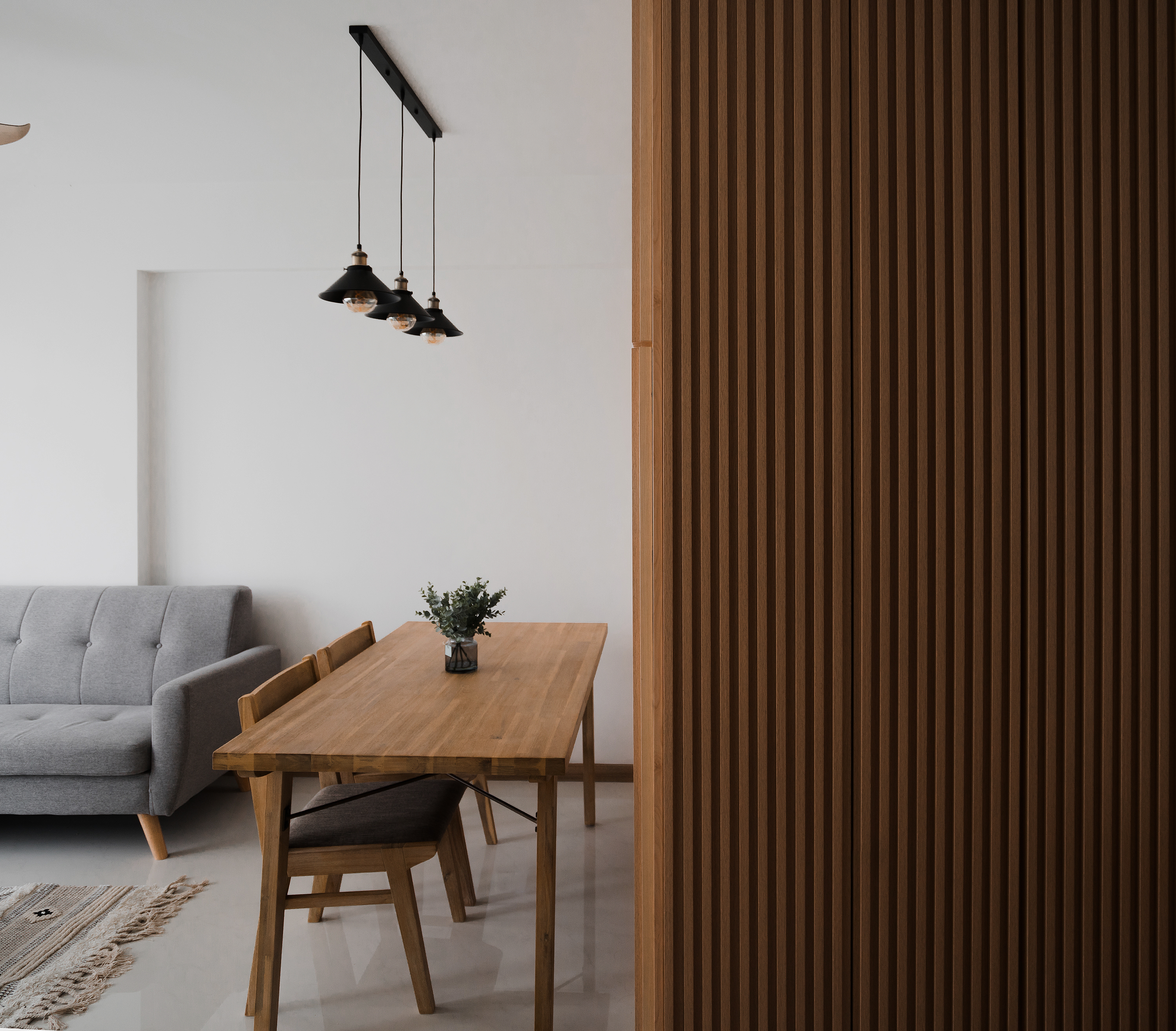 We do Dining but on the Move - Modern minimalist living room, wooden dining table, gray sofa, wooden chairs, textured wall
