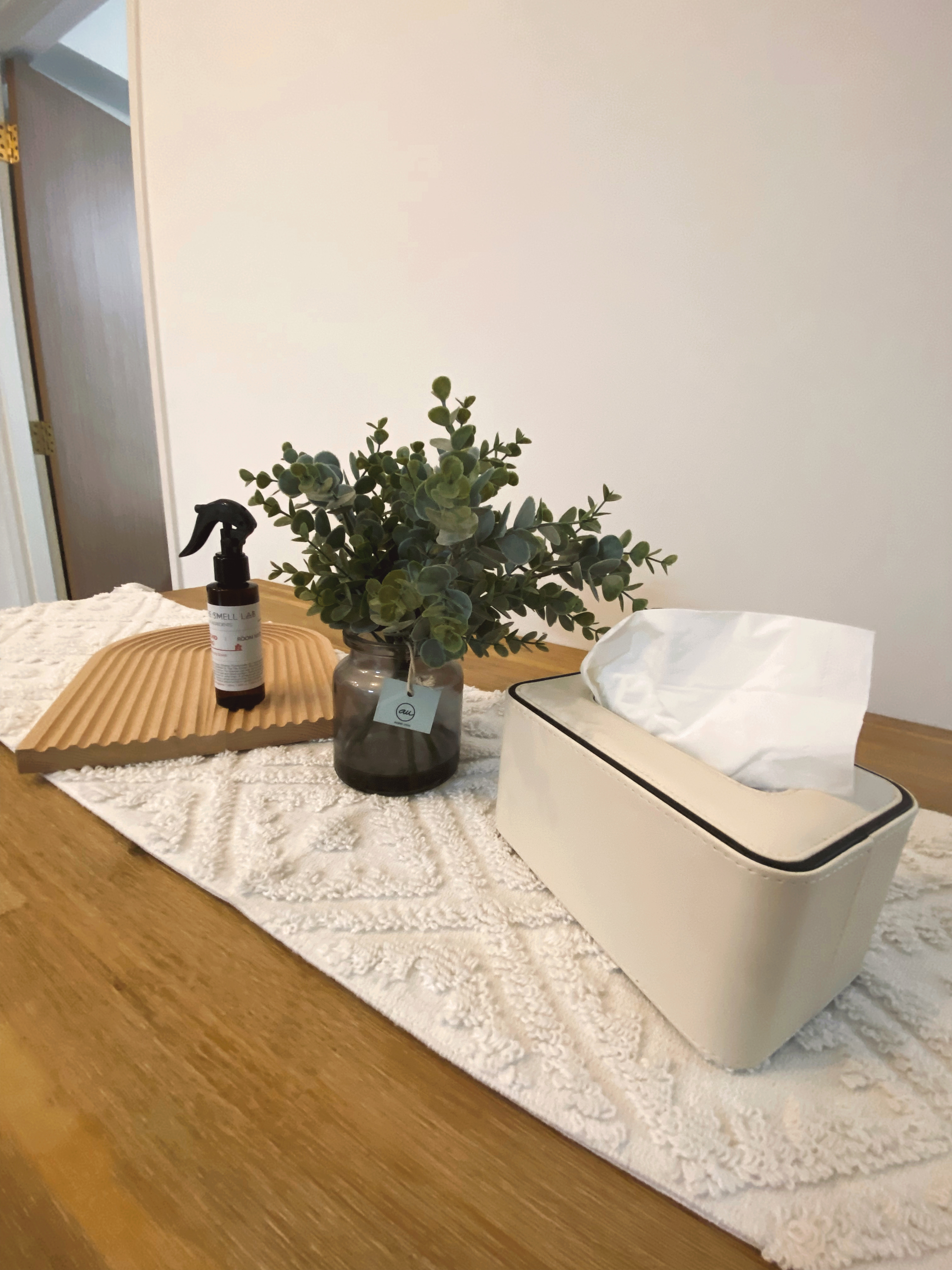 We do Dining but on the Move - vibrant green plant, wooden tray, white textured rug, beige storage bin, white tissue box