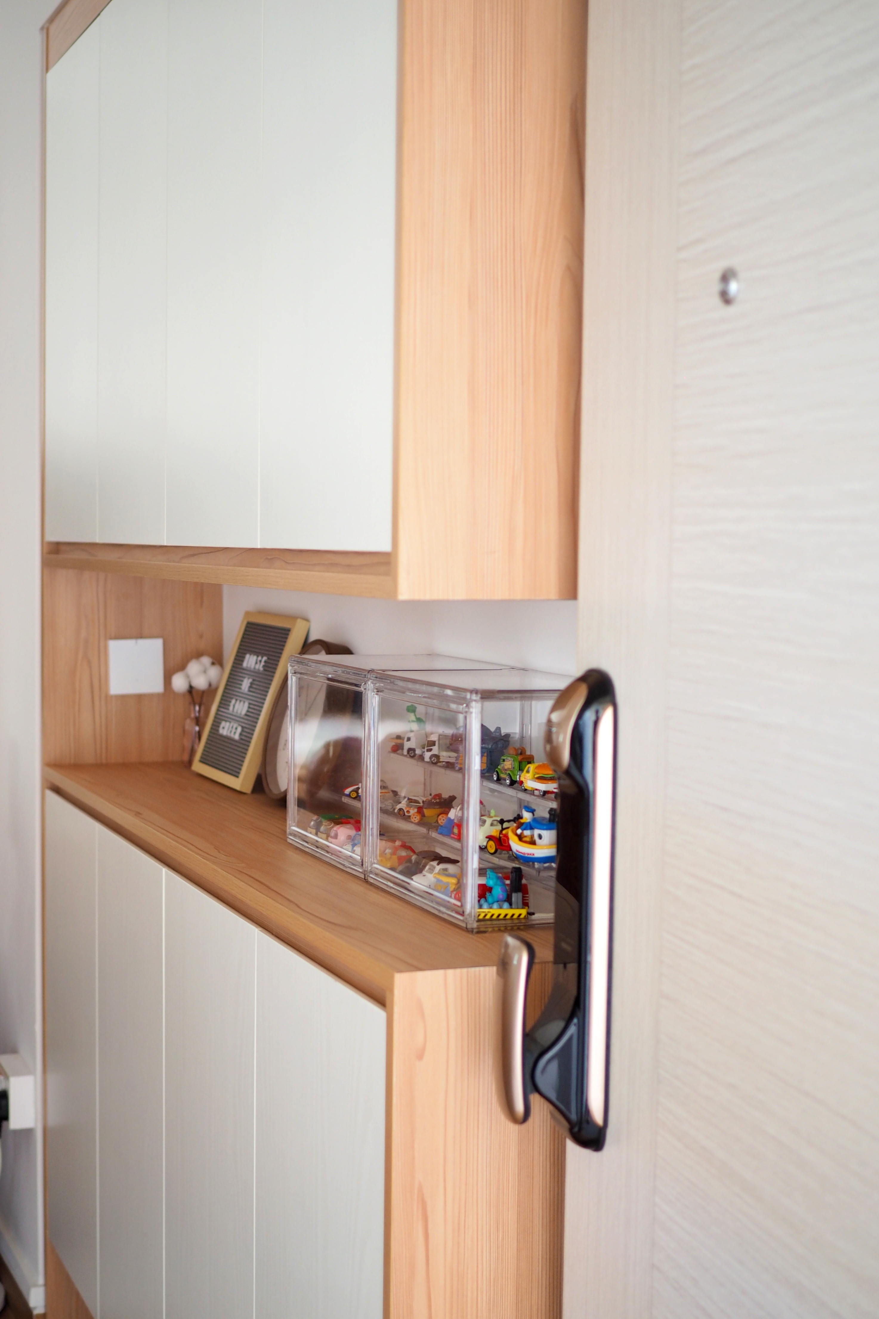 Minimalist home decor for a clutter-free home - Wooden cabinet with open door, toy cars in clear containers, chalkboard with
