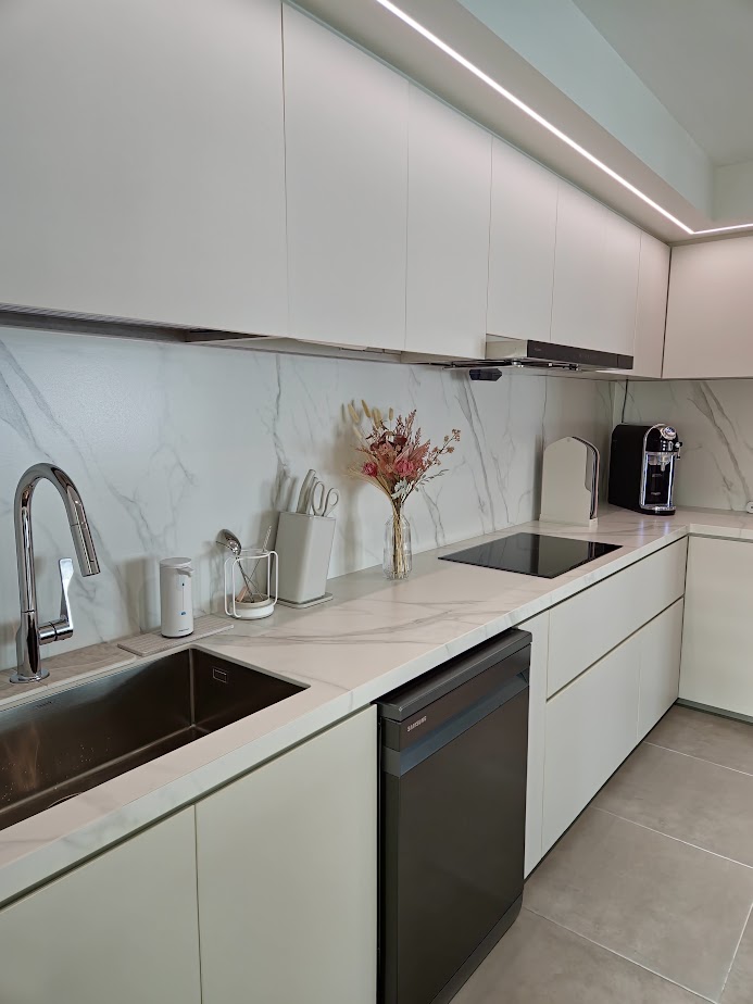 A Smart and Functional Kitchen - White kitchen cabinetry, marble backsplash, sleek stainless steel sink, modern faucet
