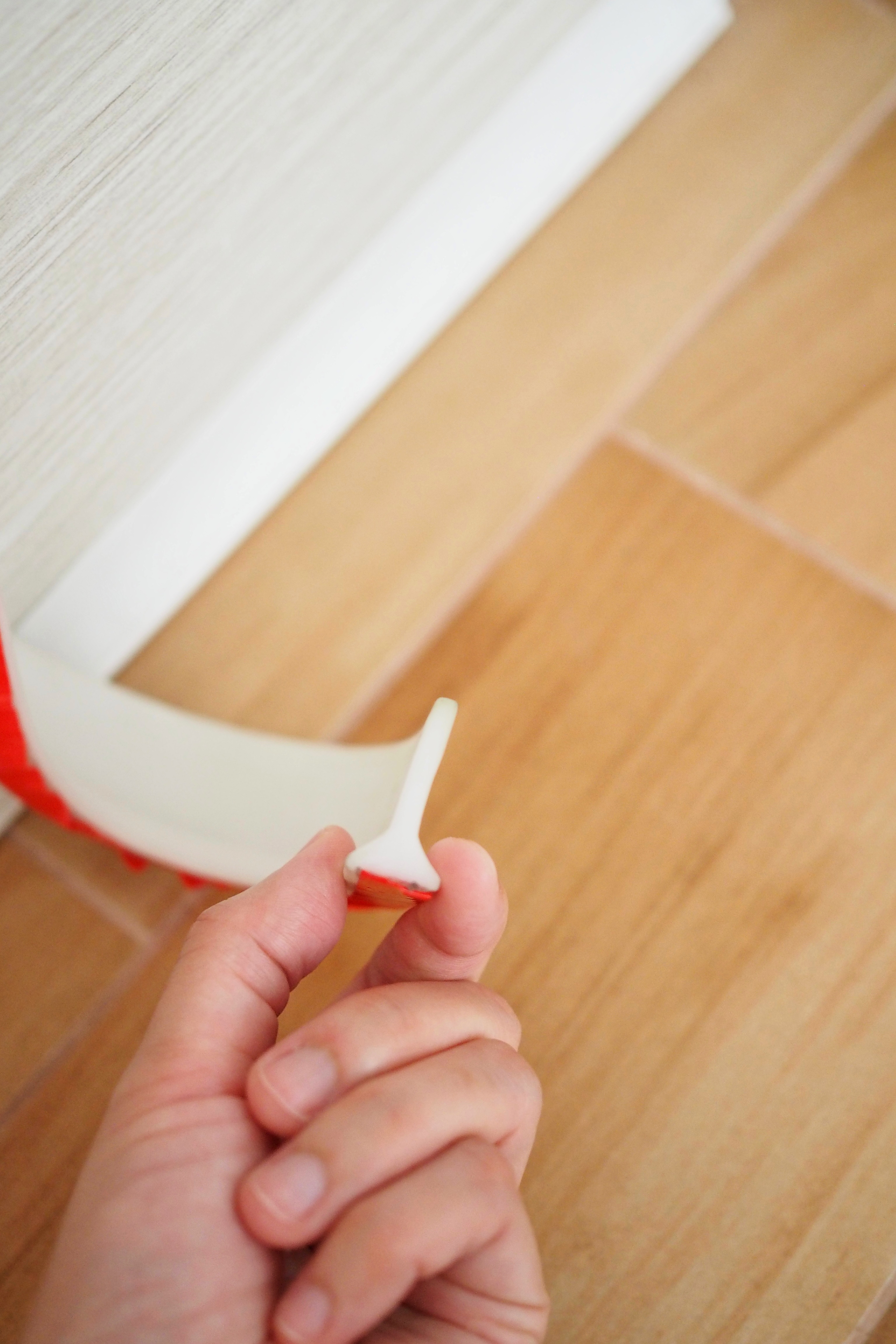 DIY: Keeping dust, smoke and pests out of our house - Hand holding red and white tool, tile floor, wooden wall, wooden floor