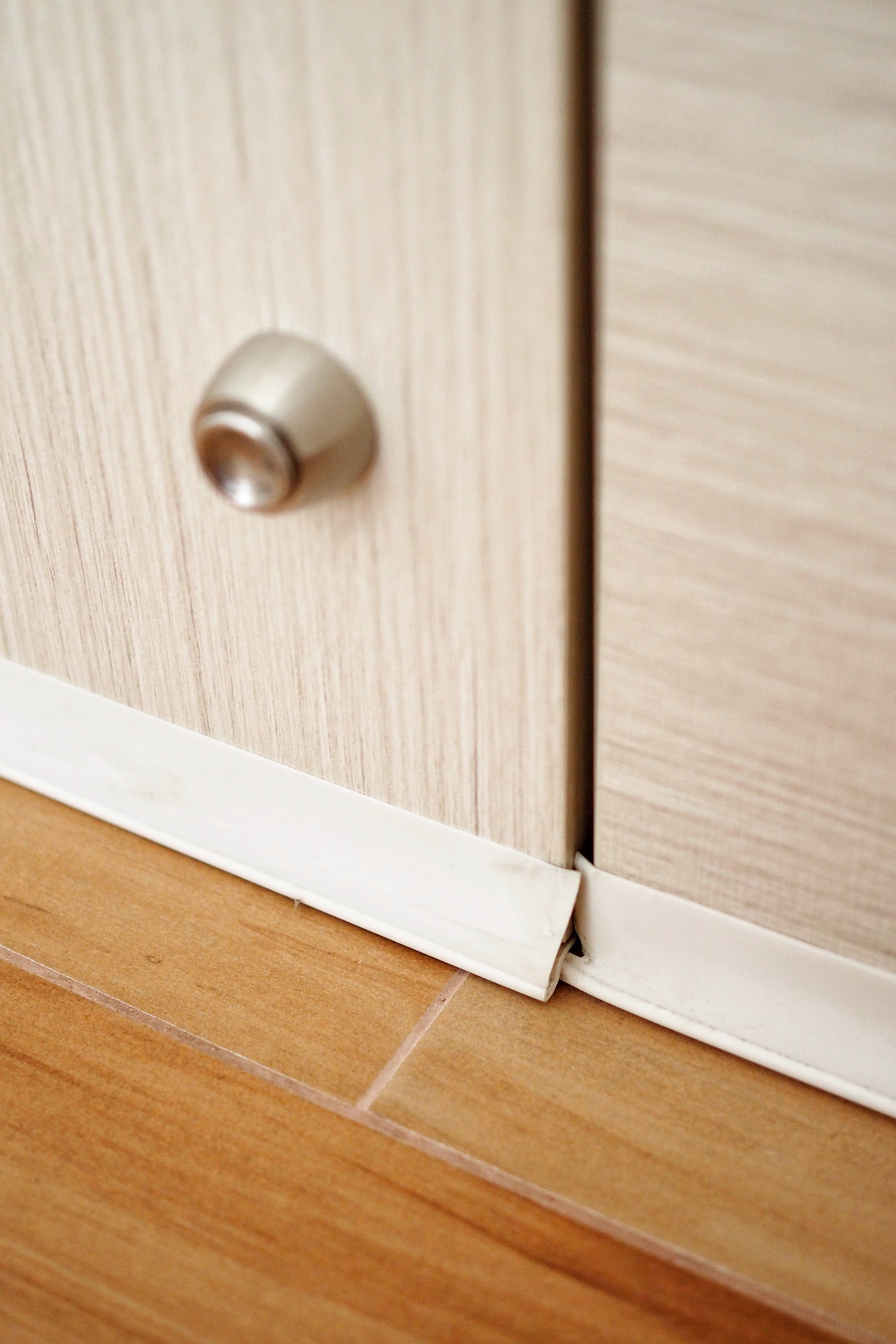 DIY: Keeping dust, smoke and pests out of our house - Light wood cabinet door handle, white trim detail, wooden floor, corner