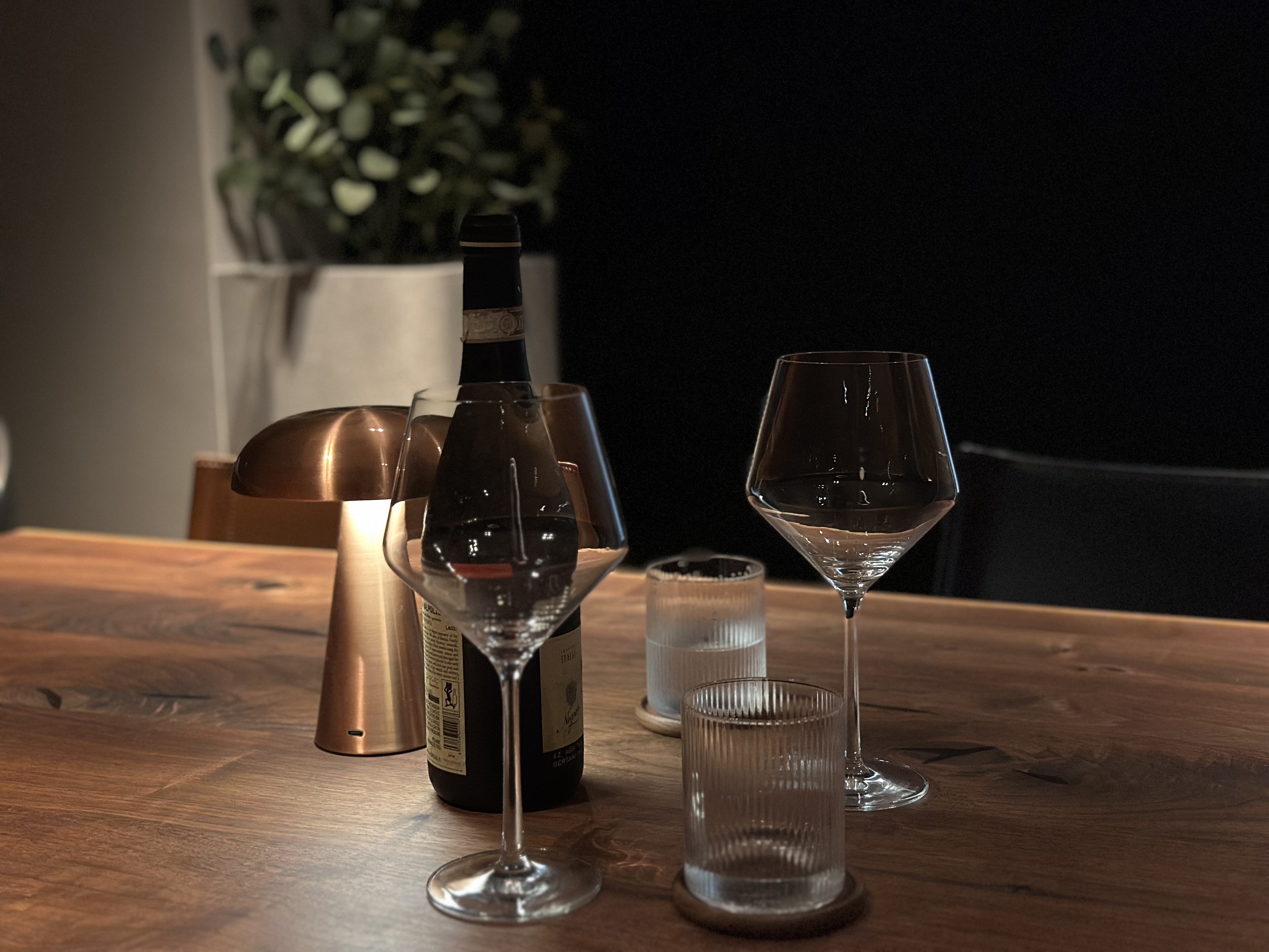 Where conversations, food, games and wine flow - wooden table, elegant setting, wine glasses, minimalist design