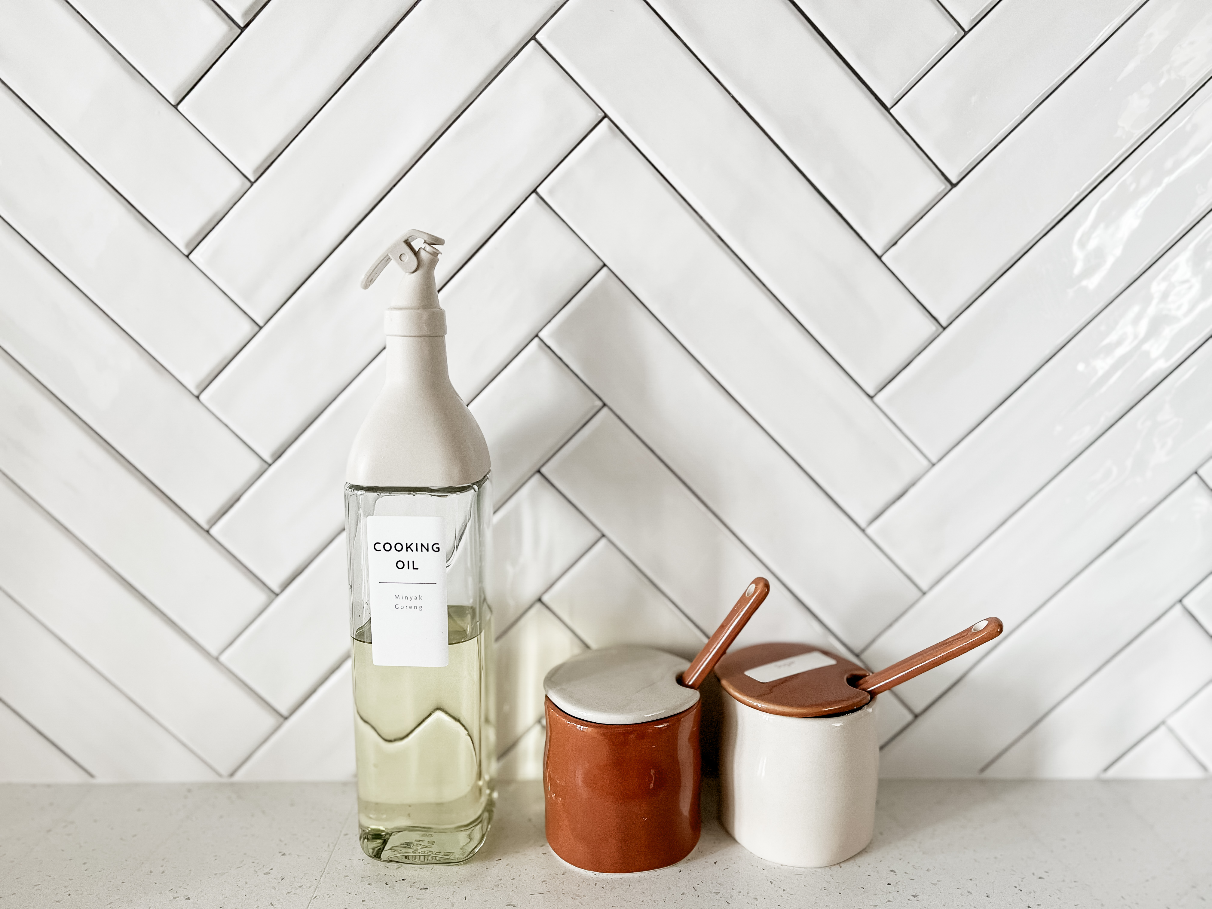 Kitchen - Seasoned with love and laughter  - Glass bottle of cooking oil, white and brown ceramic containers, white tiled