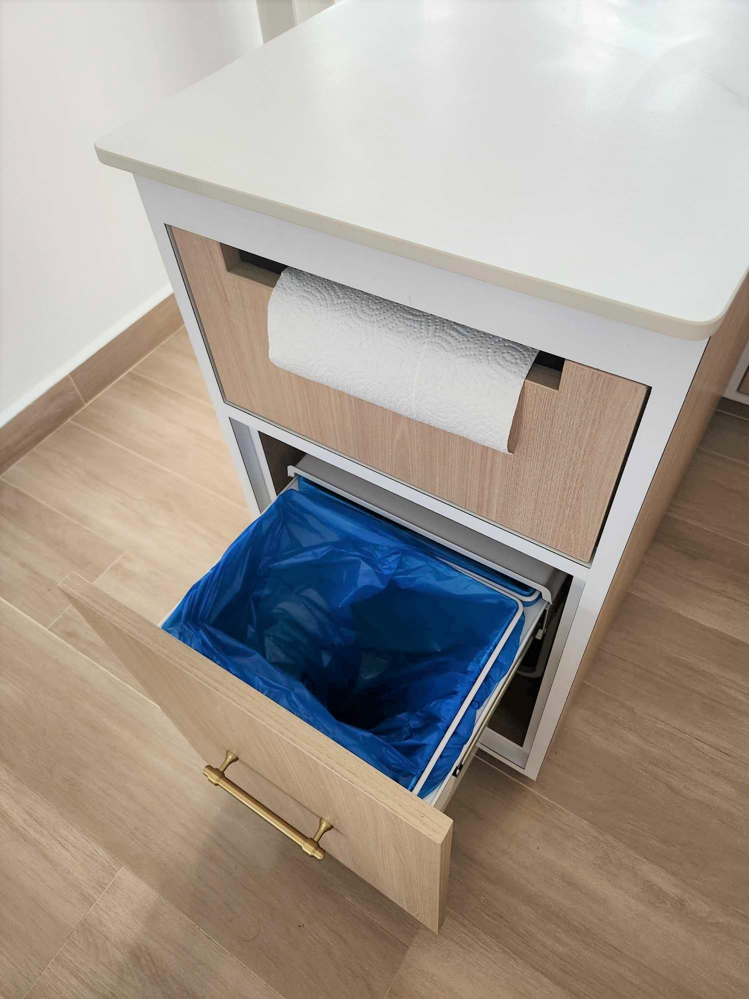 Spacious U-shaped kitchen  - White kitchen island, wooden drawers, blue trash bin, white countertop, light wooden cabinets