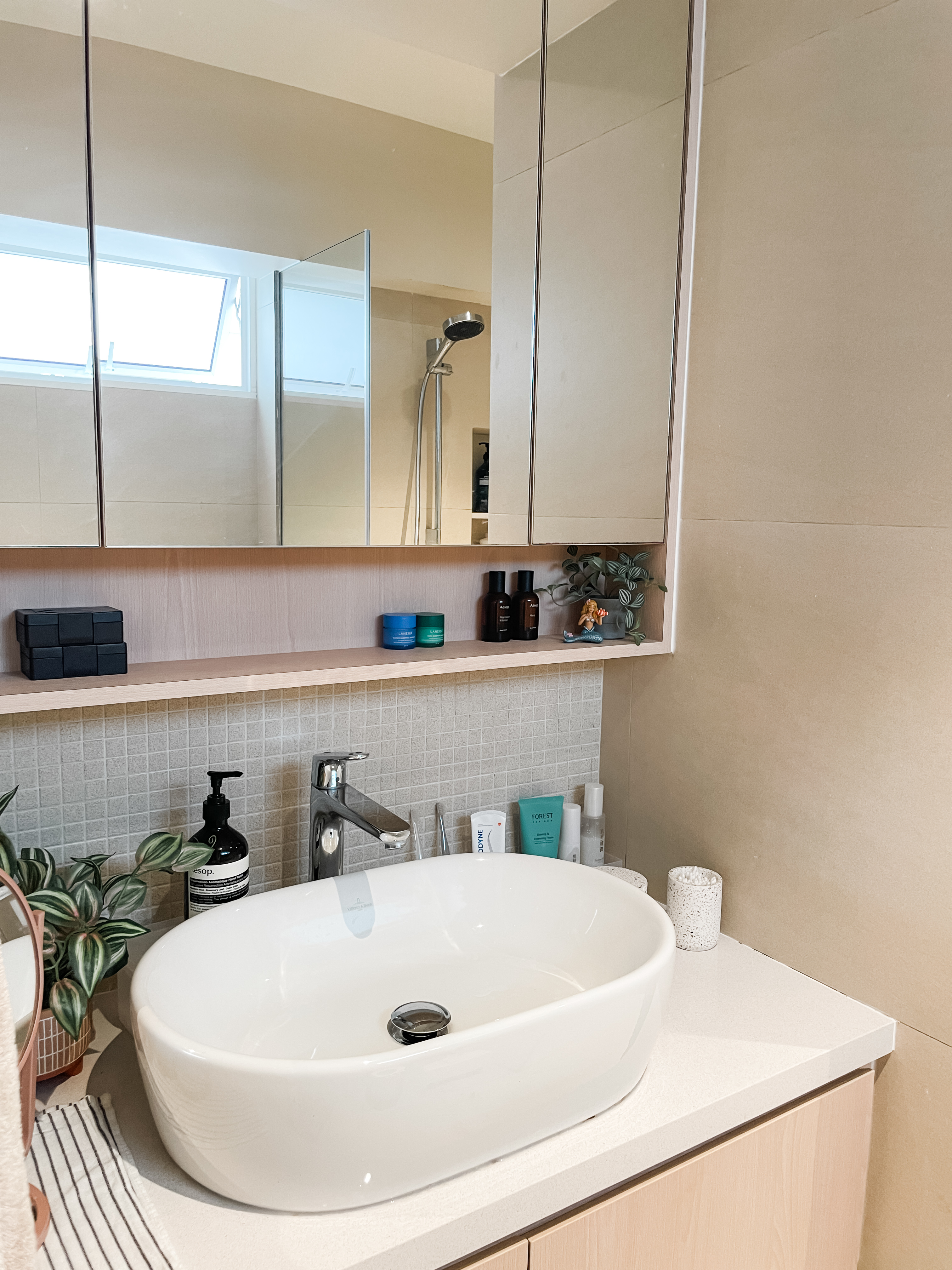 Bathrooms That Evoke The Sand & The Sea - White oval sink, beige countertop, modern bathroom, large mirror, built-in shelves