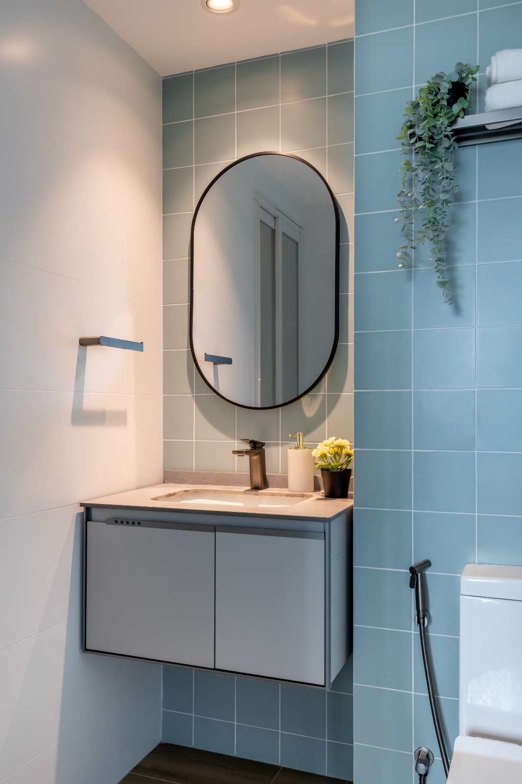 The most expensive tile is in this toilet!  - Modern bathroom with light blue tiles, sleek white cabinets, large oval mirror
