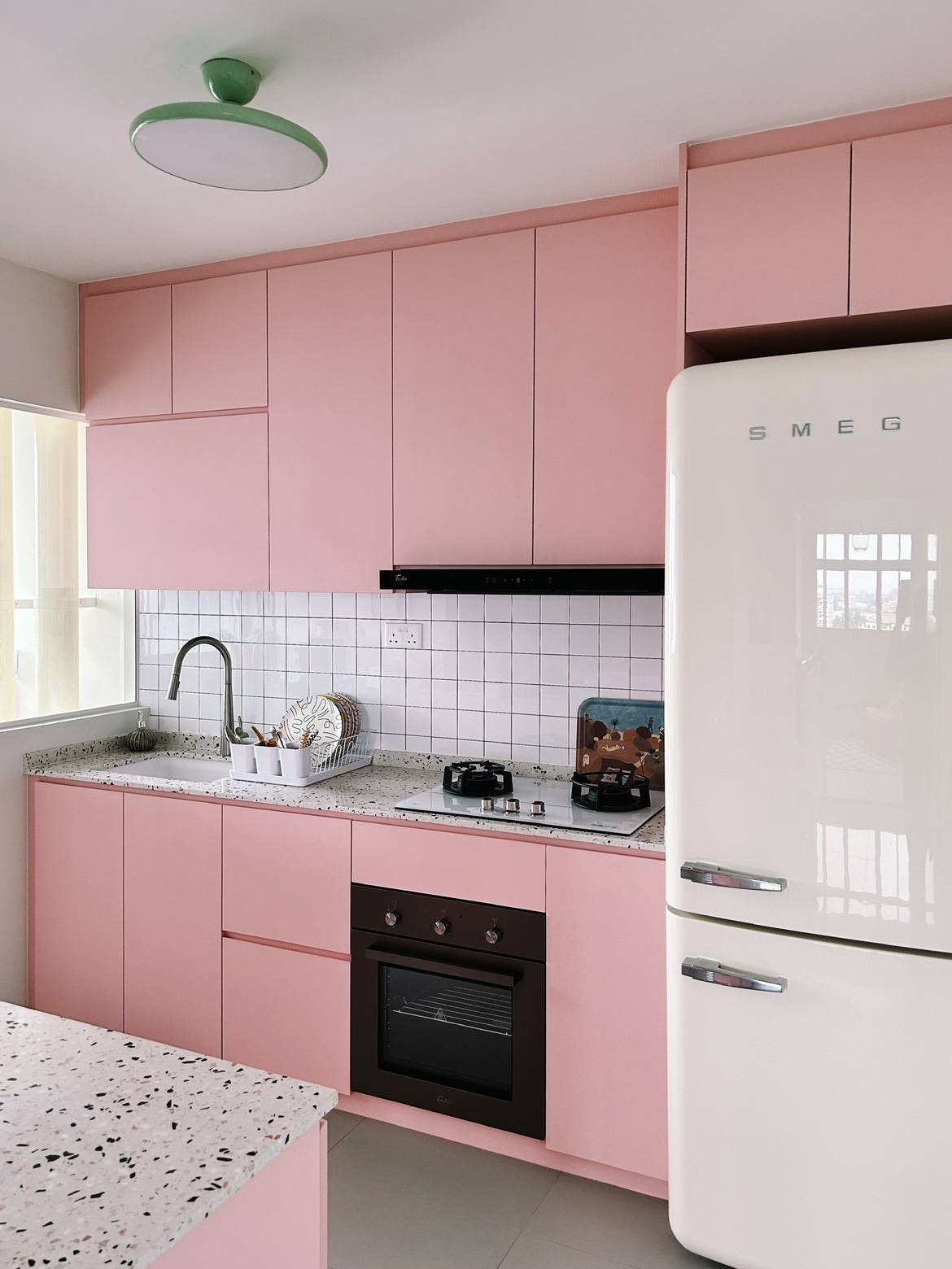 A pink kitchen because why not! - Pink kitchen cabinets, white tiled backsplash, black range hood, speckled granite