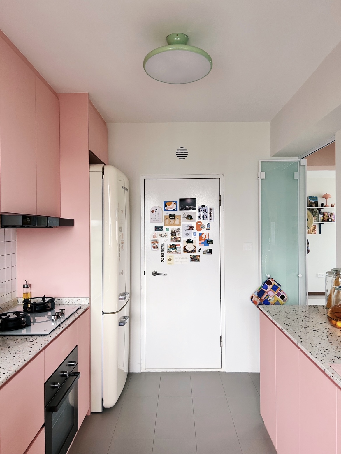 A pink kitchen because why not! - Pink kitchen with modern appliances, white refrigerator adorned with various magnets, light
