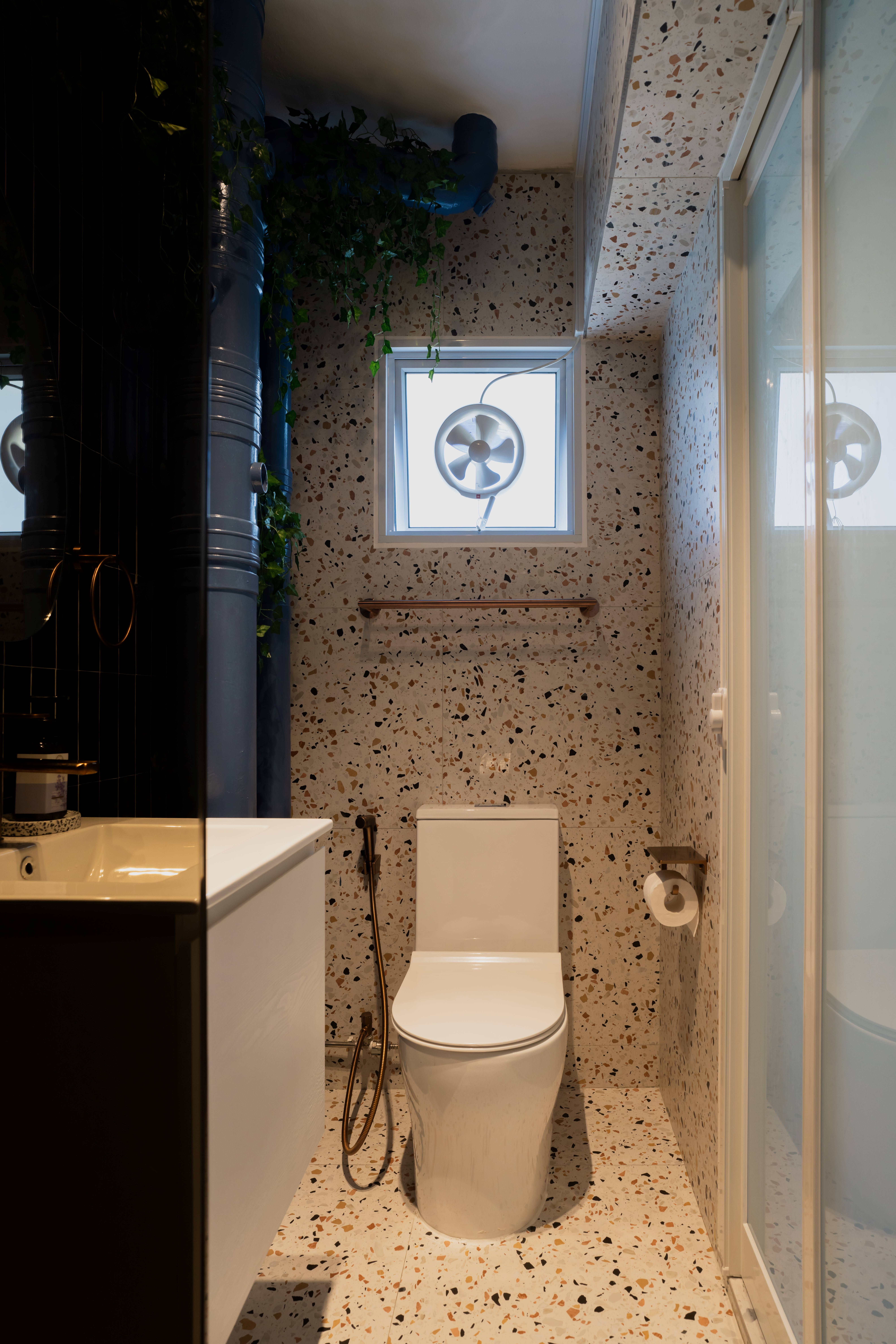 Bathroom edition: Boutique vibes and style  - Modern bathroom with speckled tile floor, white toilet, black vanity with gold