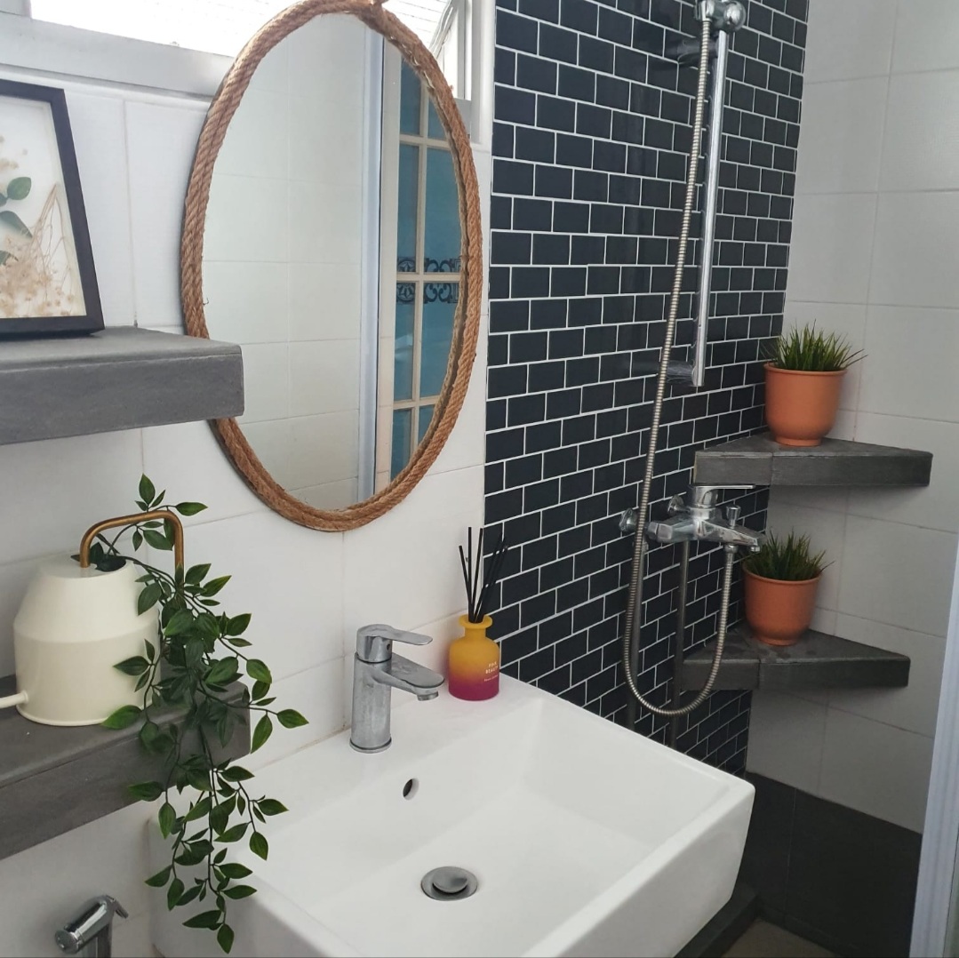 Unrenovated Bathroom - White sink, black tiles, modern bathroom, gray countertop, round mirror, potted plants, white ceramic