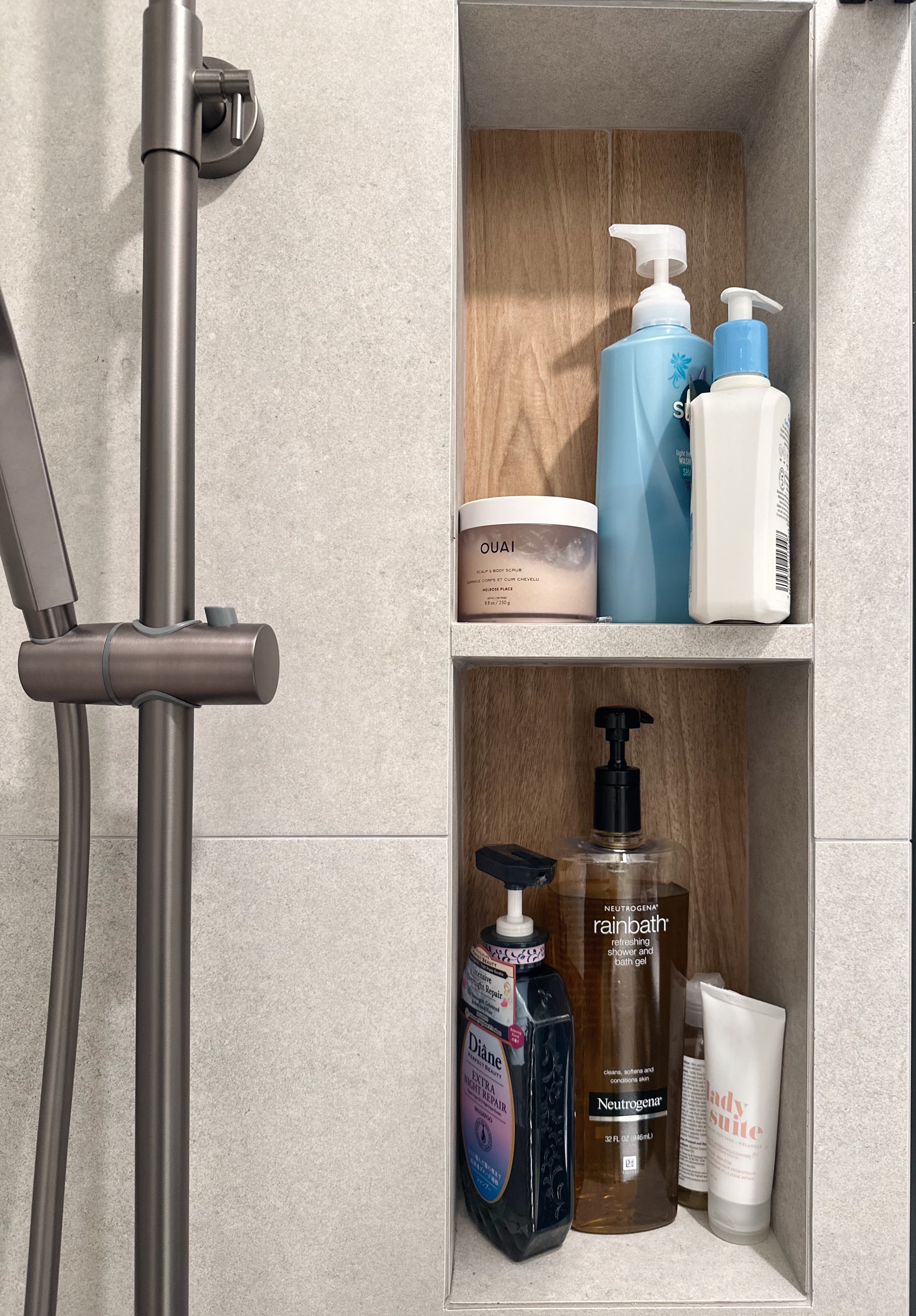 Neutral with a Pop of Colour ✨🧻 - Shower area with neatly organized toiletries, metallic shower head, wooden shelf, blue and