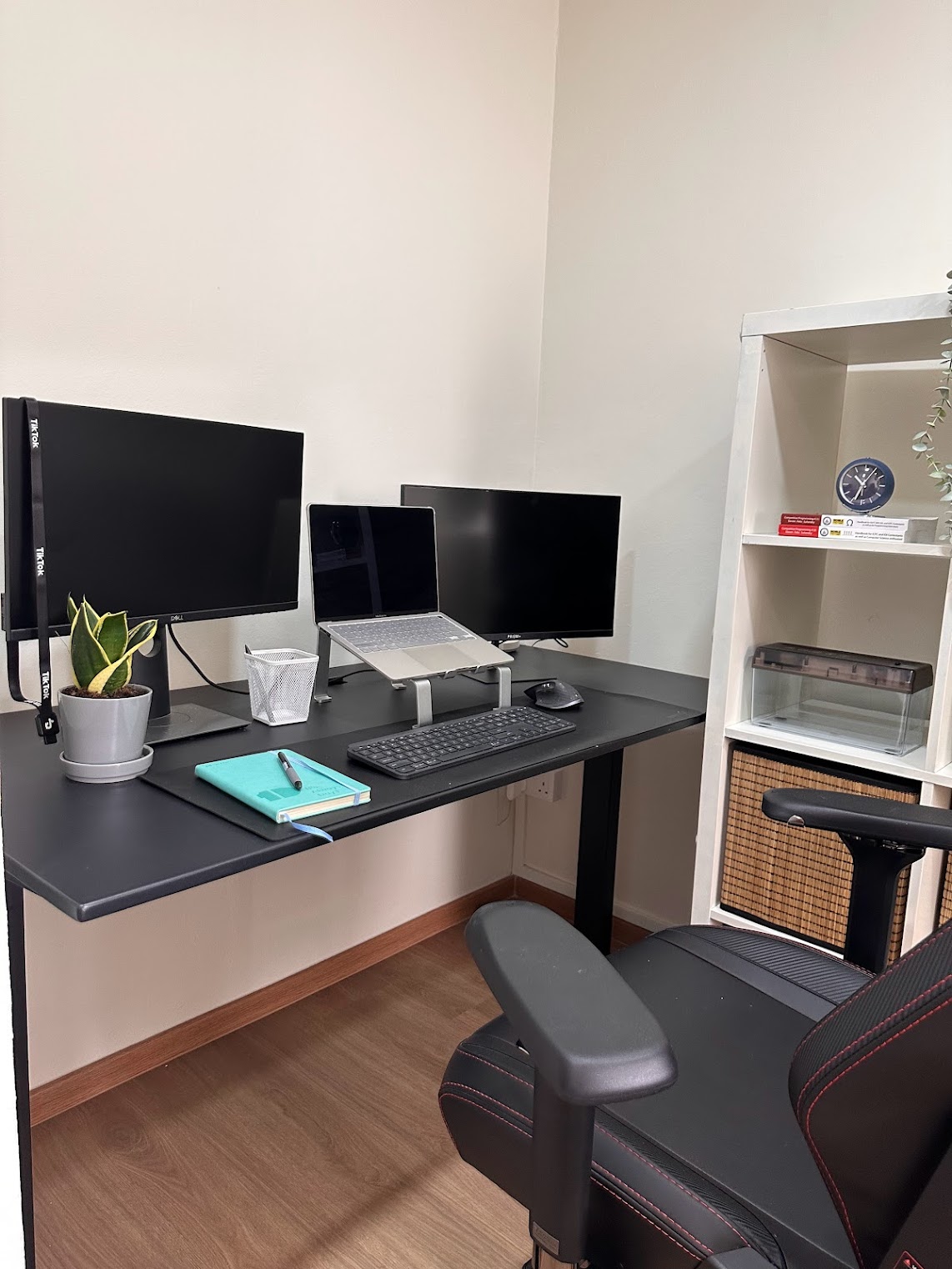 Home Office Within The Bedroom - Black desk with dual monitors, sleek black keyboard, ergonomic black office chair, small