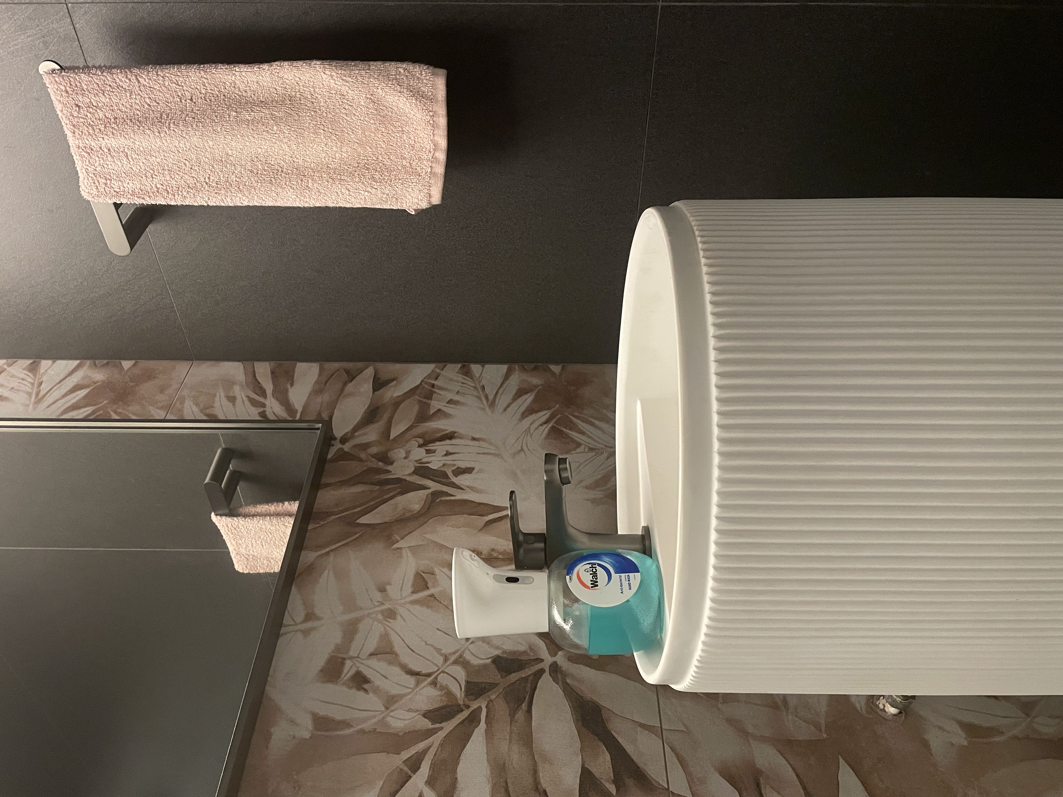 Our common toilet: The staycation villa restroom - White toilet, floral-patterned floor, beige towel, sleek sink, modern