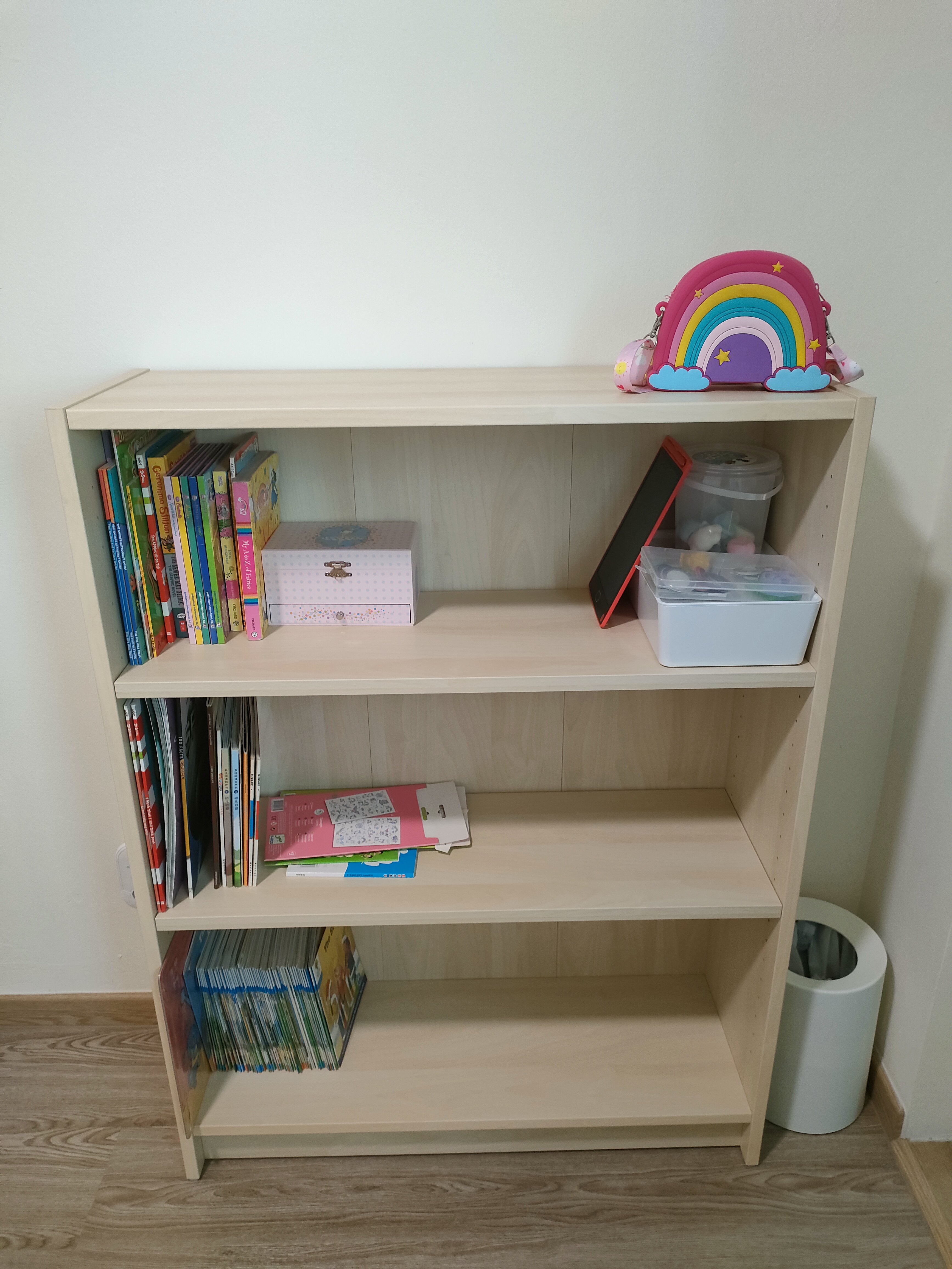Each kid gets a bedroom!  - Wooden bookshelf, light beige color, neatly organized, children's books, colorful covers, rainbow