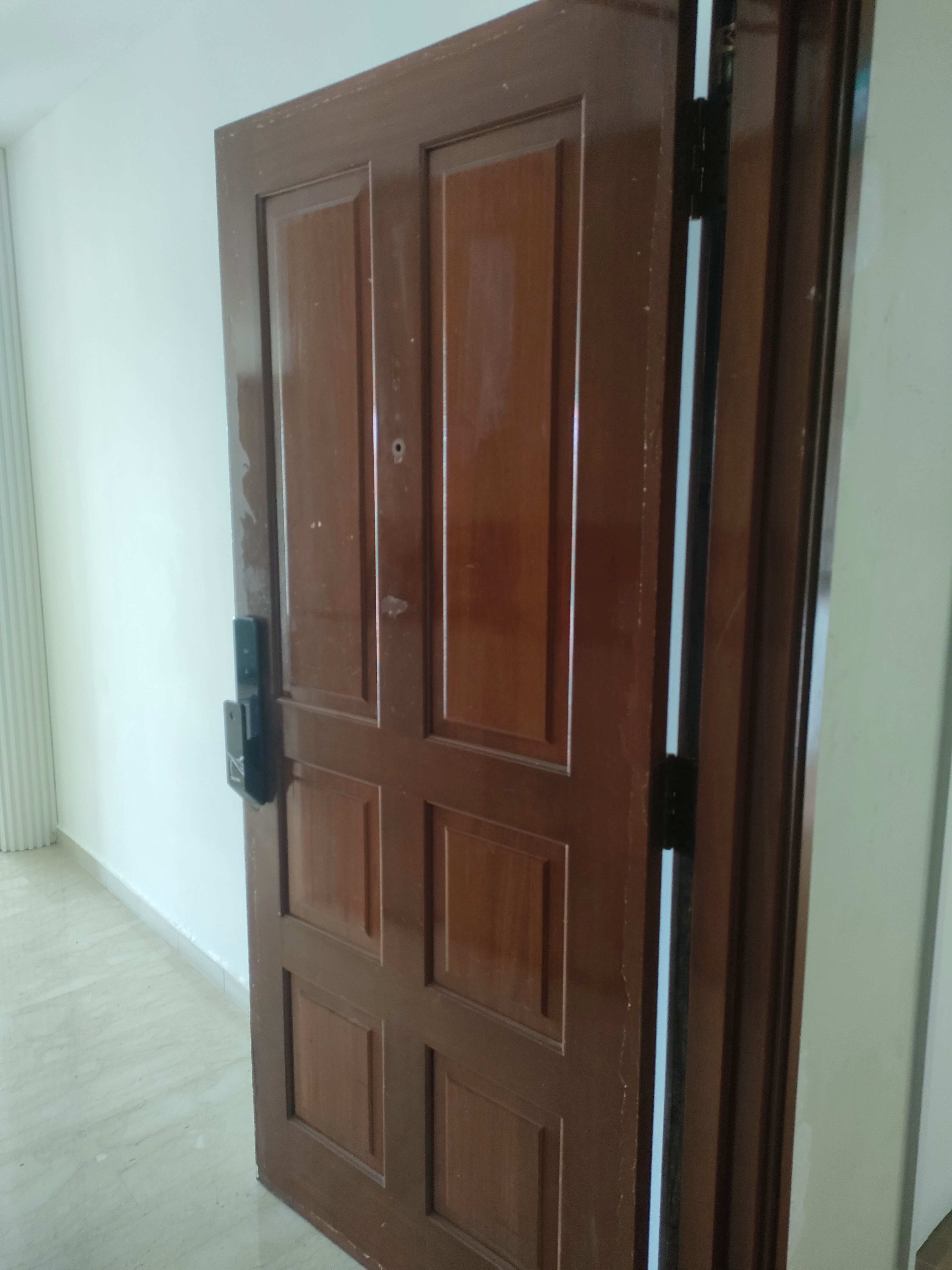 Our guests are greeted by this sight! - Wooden door, brown exterior, vertical panels, black handle, door lock, white wall
