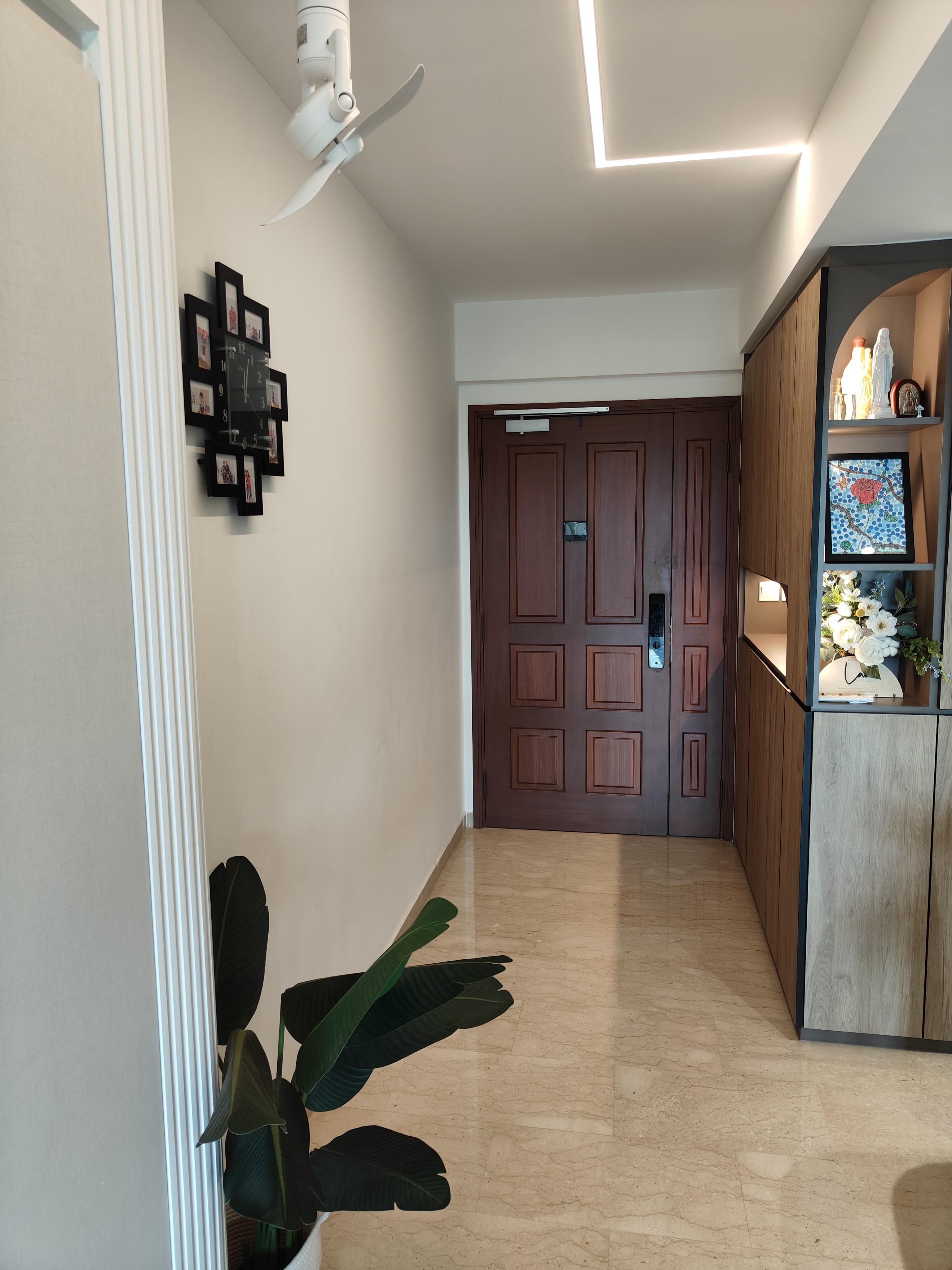 Our guests are greeted by this sight! - White ceiling fan, light fixture, wooden door, black photo frame, white wall, beige