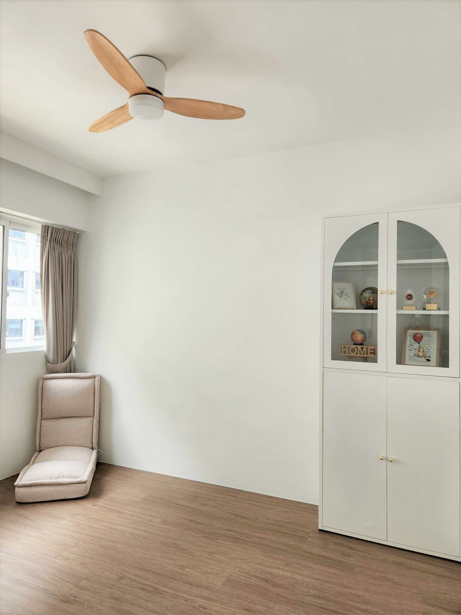 Guest room with inflatable bed for flexibility  - Wooden ceiling fan, light-colored armchair, minimalist decor, white wall