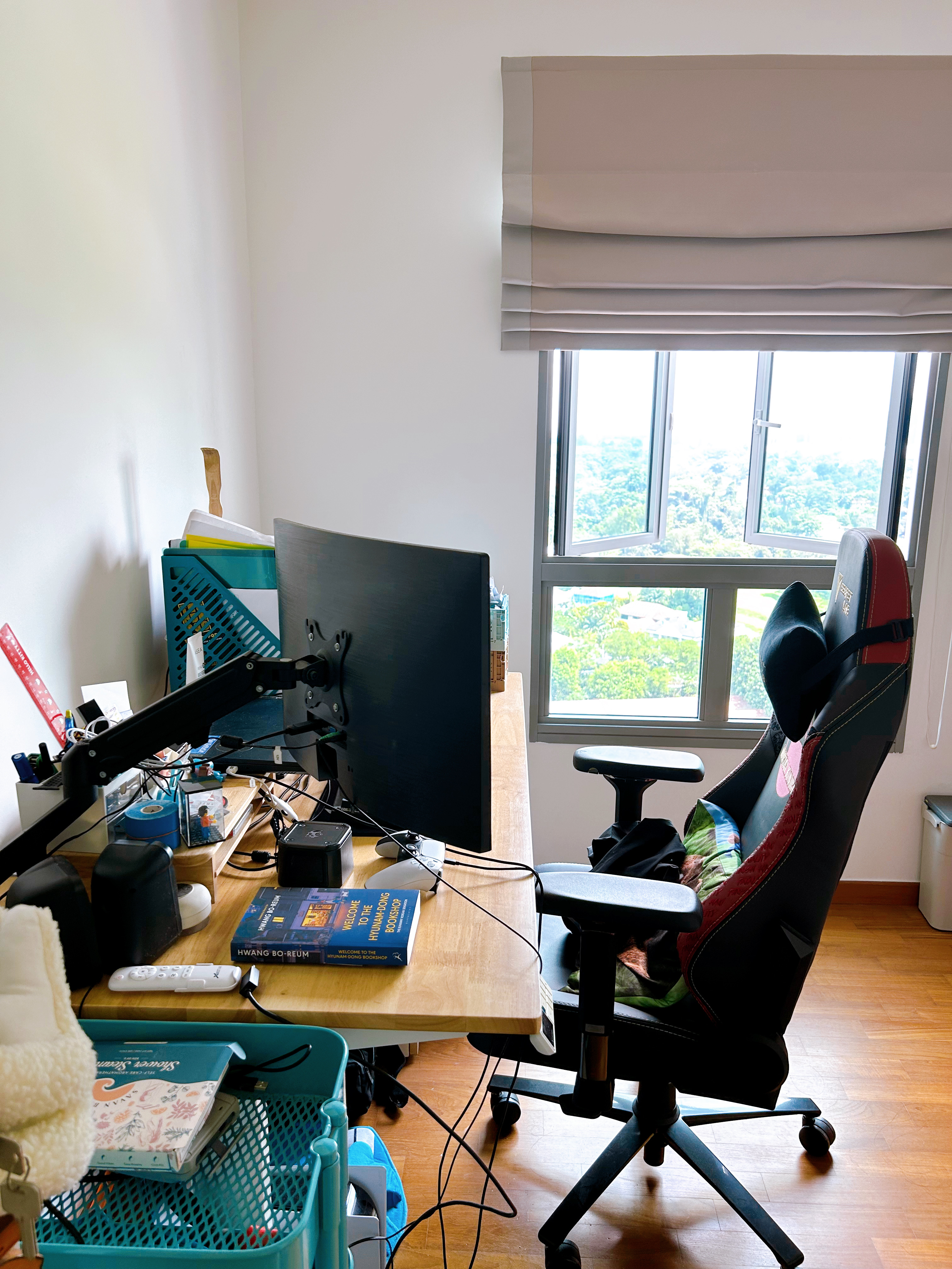 A study in a multi-functional room  - Desk with computer setup, black office chair, blue storage bin, white keyboard, black