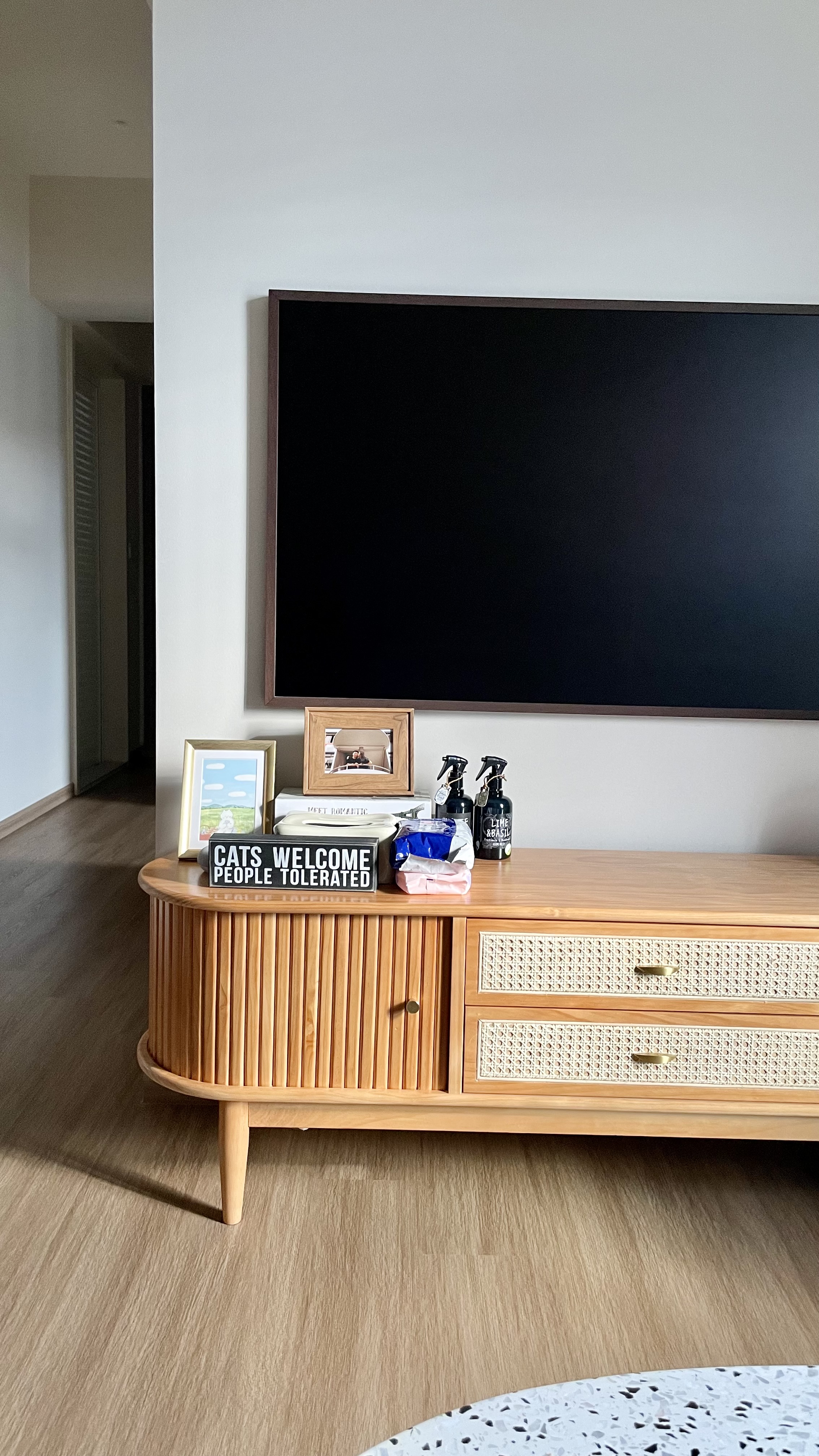 Juzz up your home with affordable aesthetic decor pieces - Wooden TV stand, black TV, framed photo, cat sign, laundry