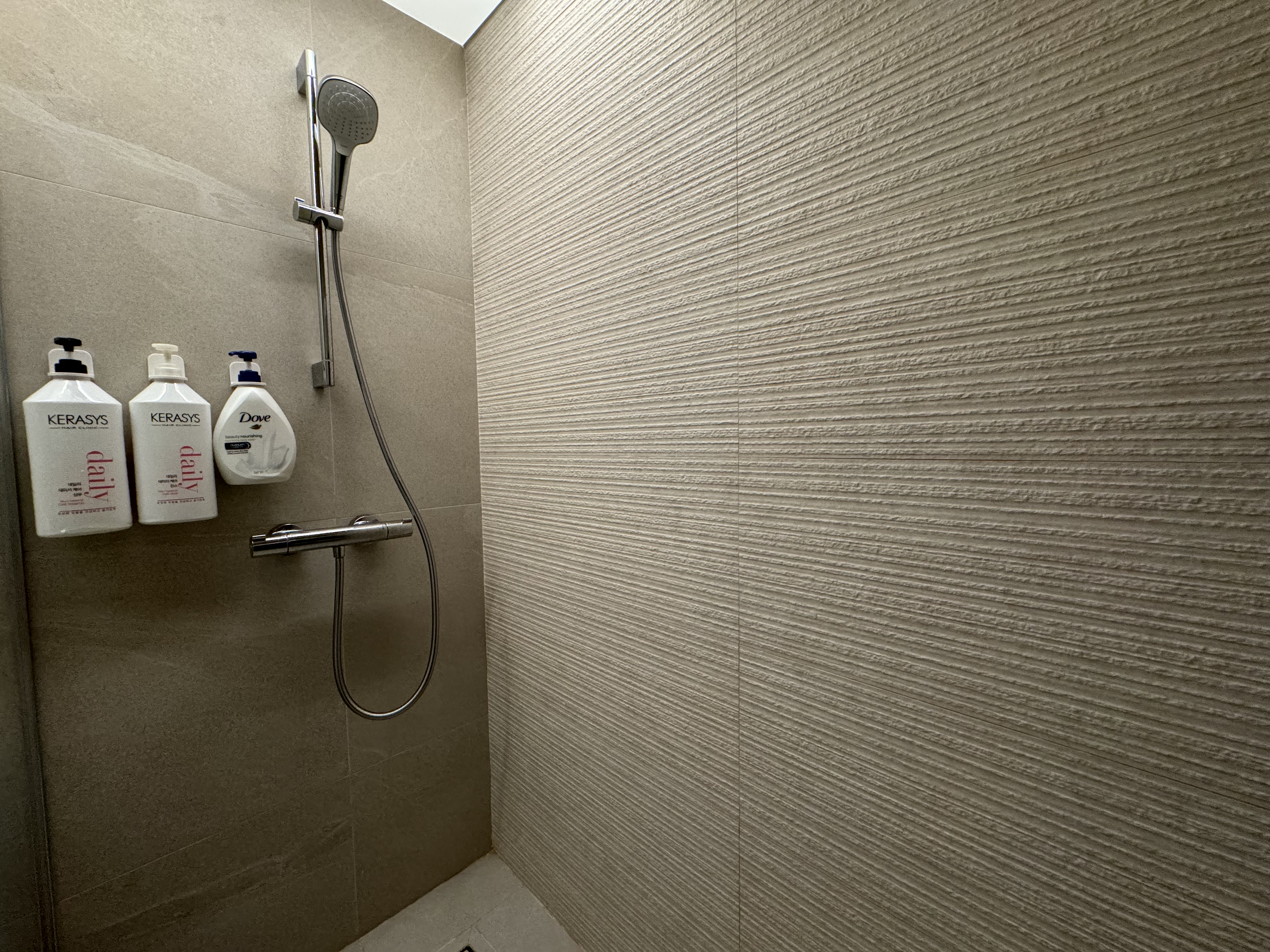 Unveiling our very personal space - bathroom!  - Shower area with sleek, beige textured tiles, modern showerhead and handheld