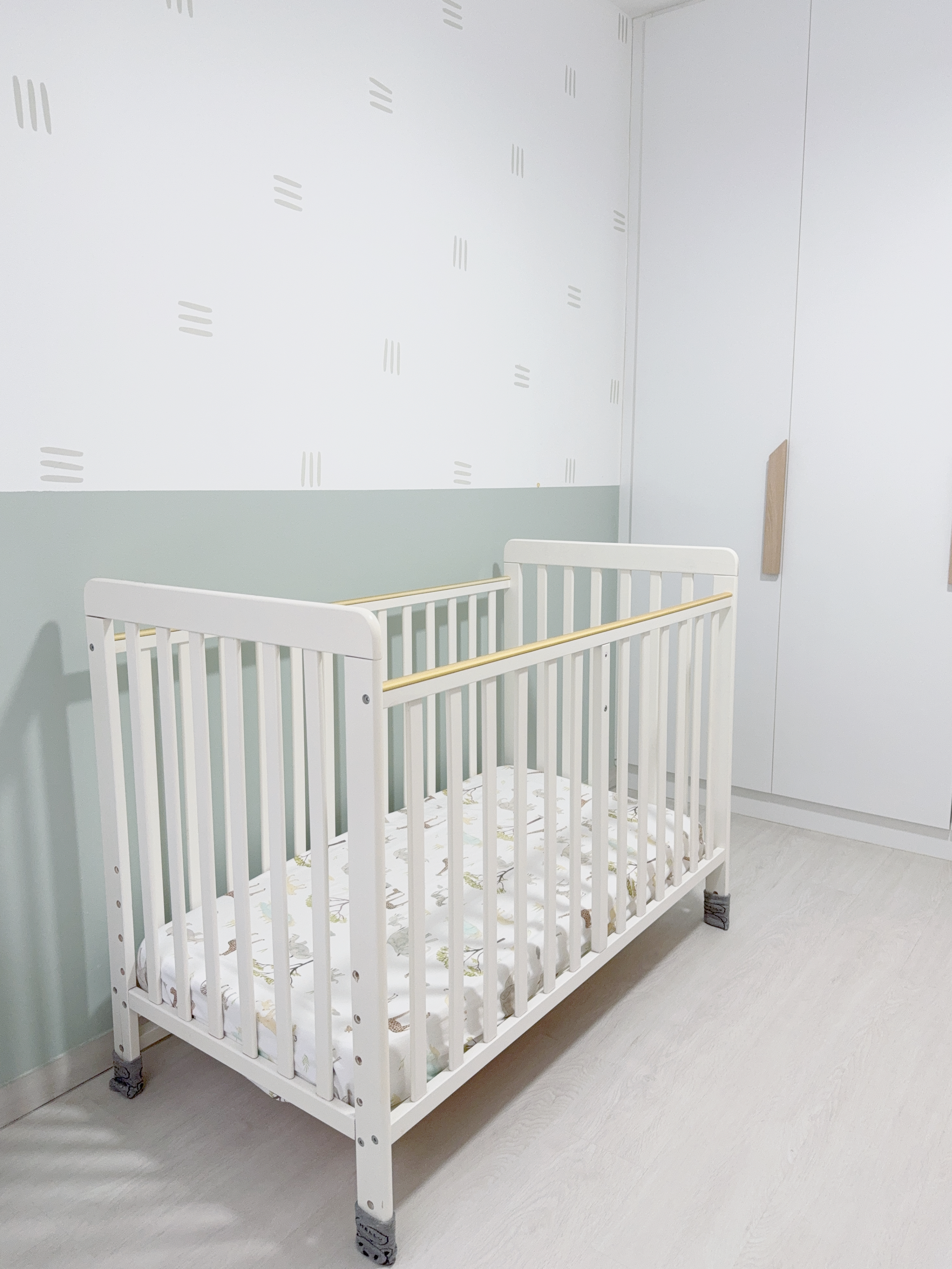 Two Kids Room, Two Different Styles! - White crib with gold railing, light green wall, minimalist decor, wooden floor, soft
