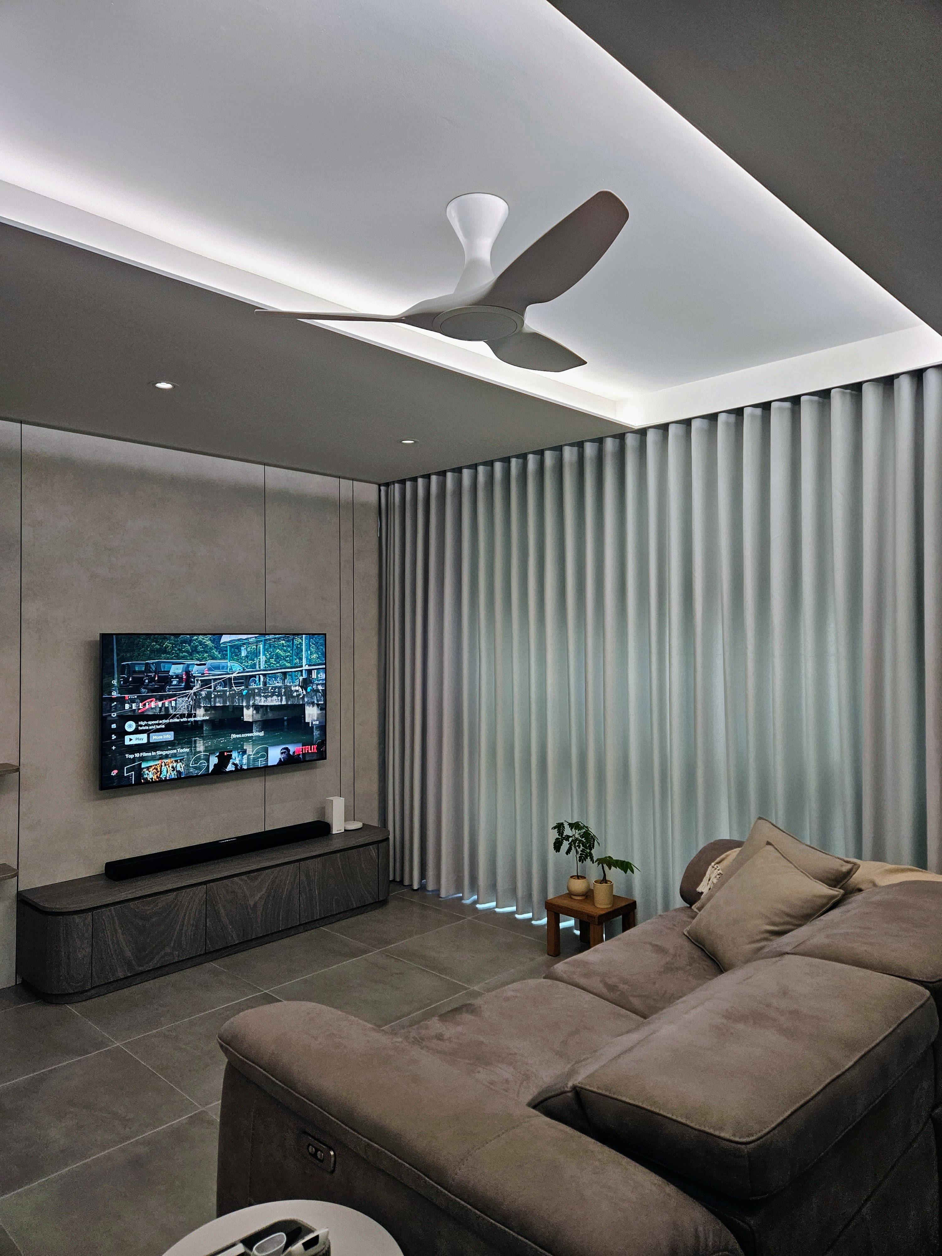 Integrating Smart Devices In Our Home - Modern living room, sleek ceiling fan, large flat-screen TV, gray walls, minimalist