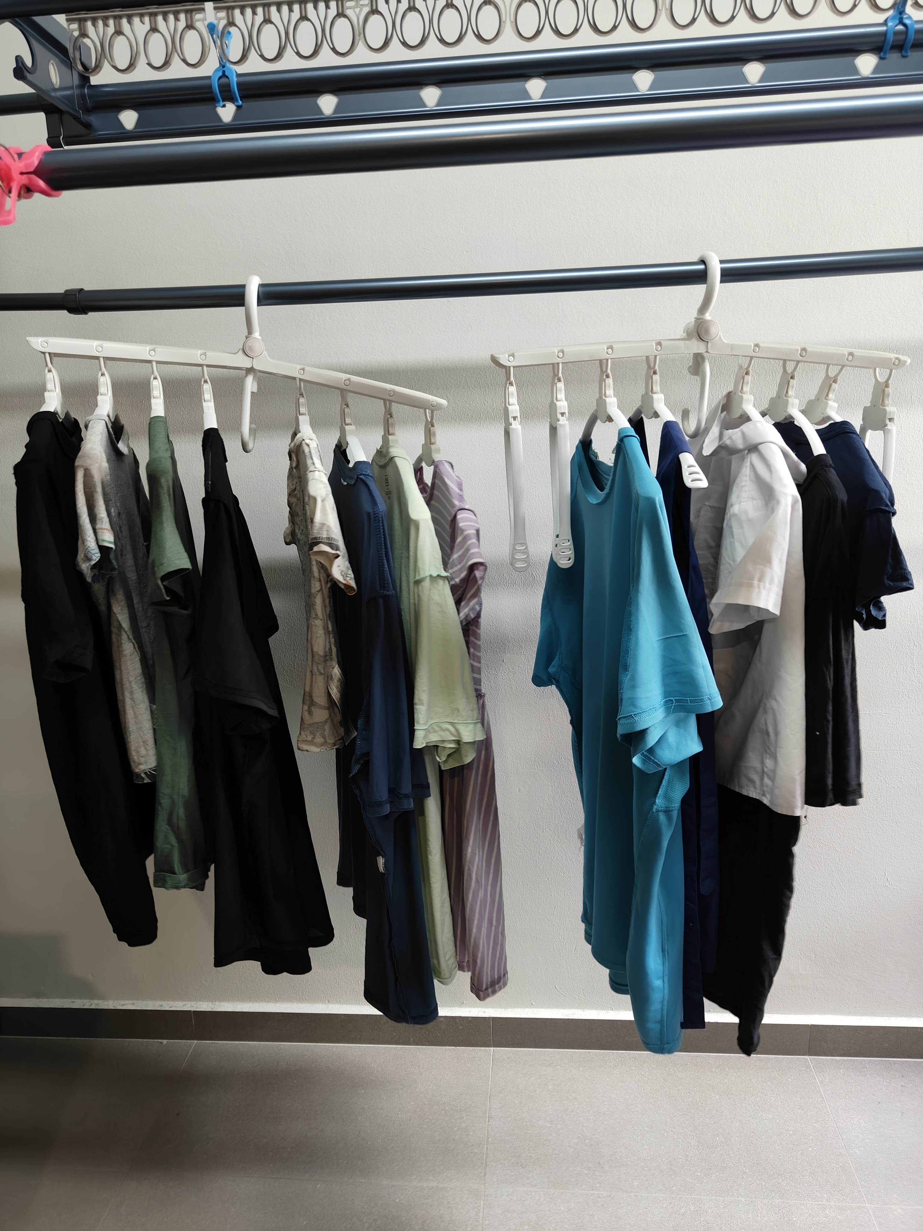 Our HOME has endless LOVE and LAUNDRY.... - Clothes hanging on white hangers, neatly organized on a rack, various colors and