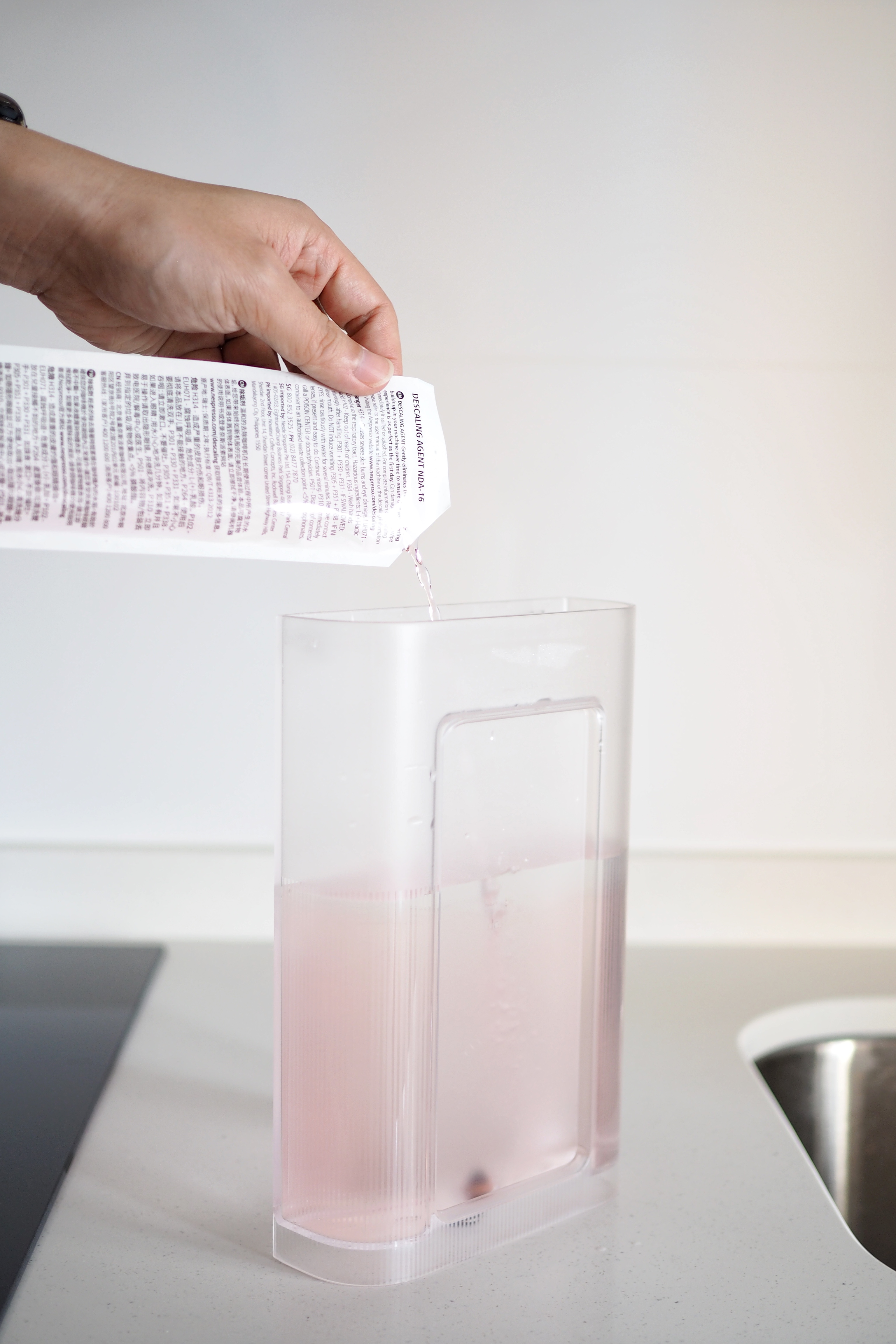 Home living: Coffee corner + delicious kopi - Clear plastic container, pink liquid, pouring process, person's hand, white
