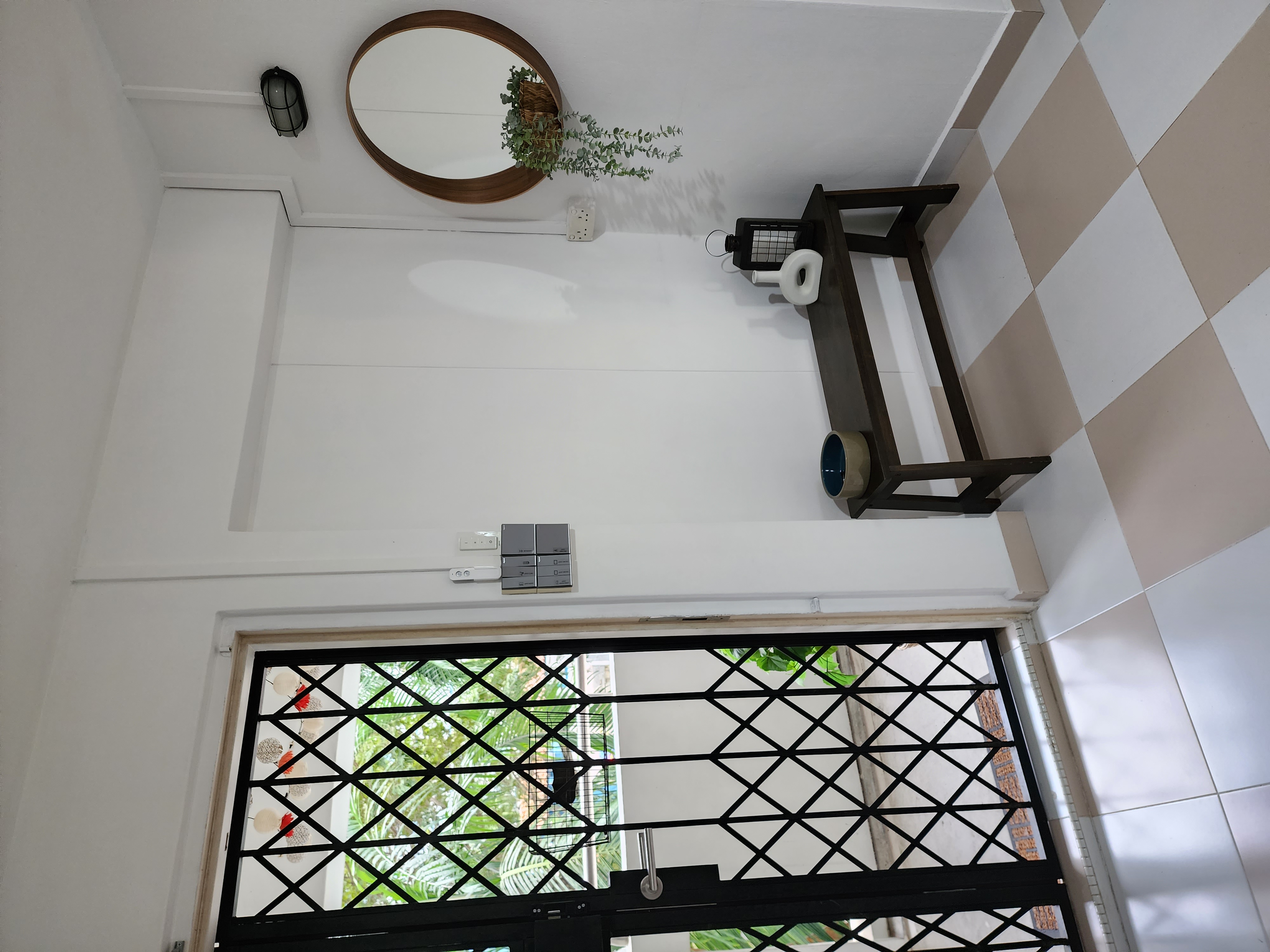 First Impression Matters - Entryway - Wooden round mirror, white wall, green plants, black lantern, white electrical outlet