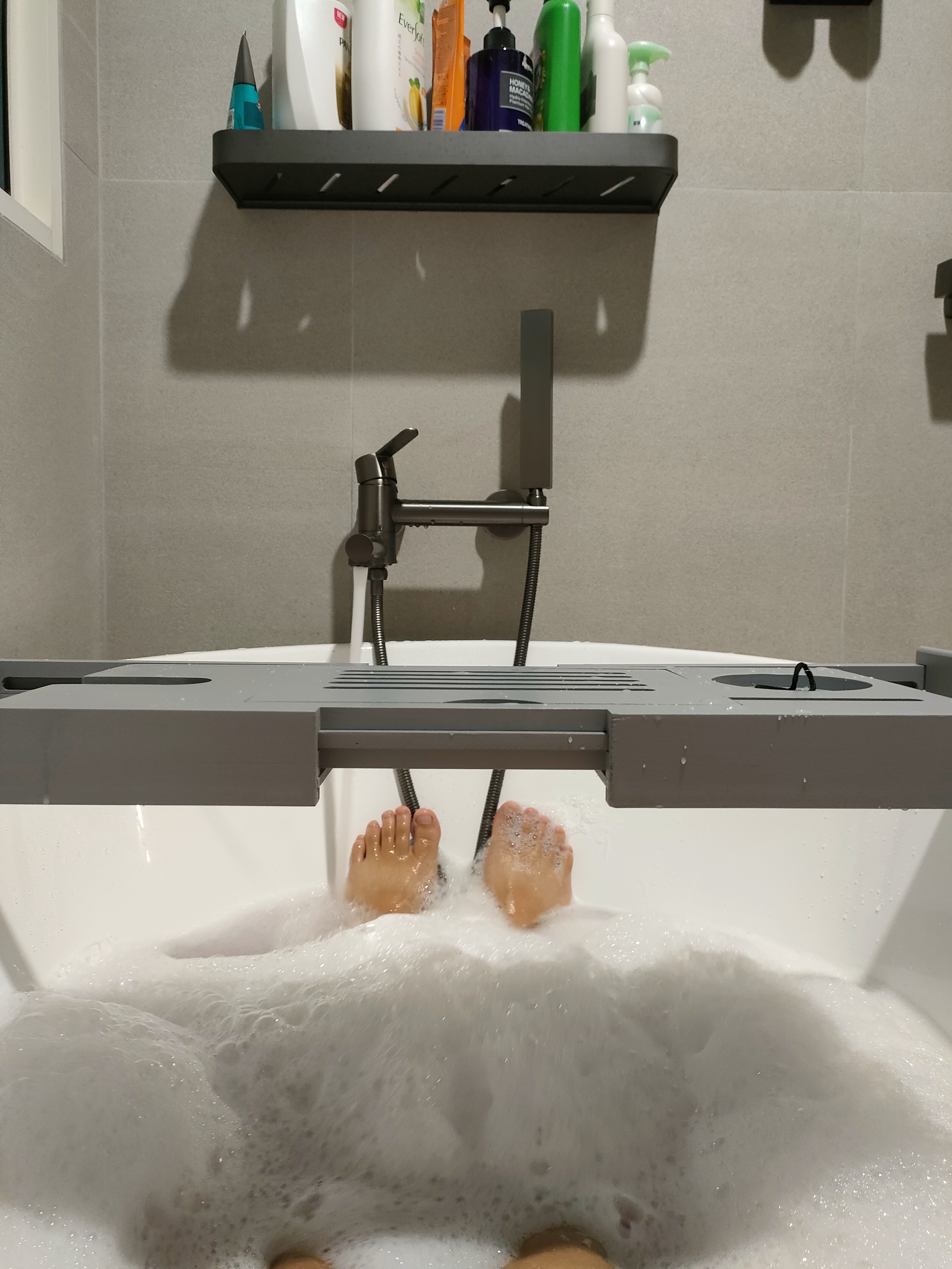 What makes the house our home... - Bathtub, bubble-filled, person's feet, soapy water, showerhead, bathroom shelf