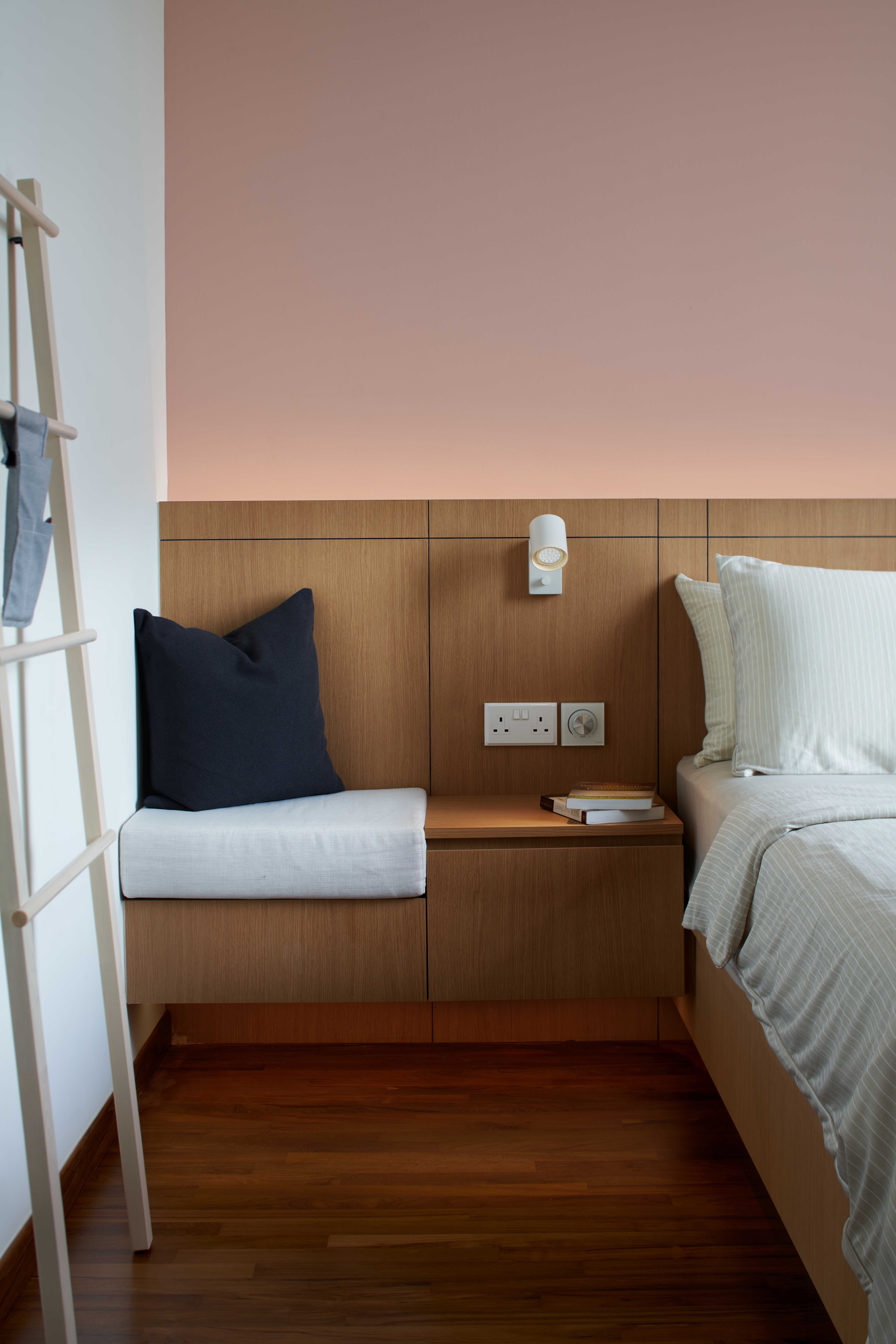 Crafting A Whimsical & Airy Home - Wooden nightstand with books, bedside lamp, wall-mounted light fixture, wooden headboard