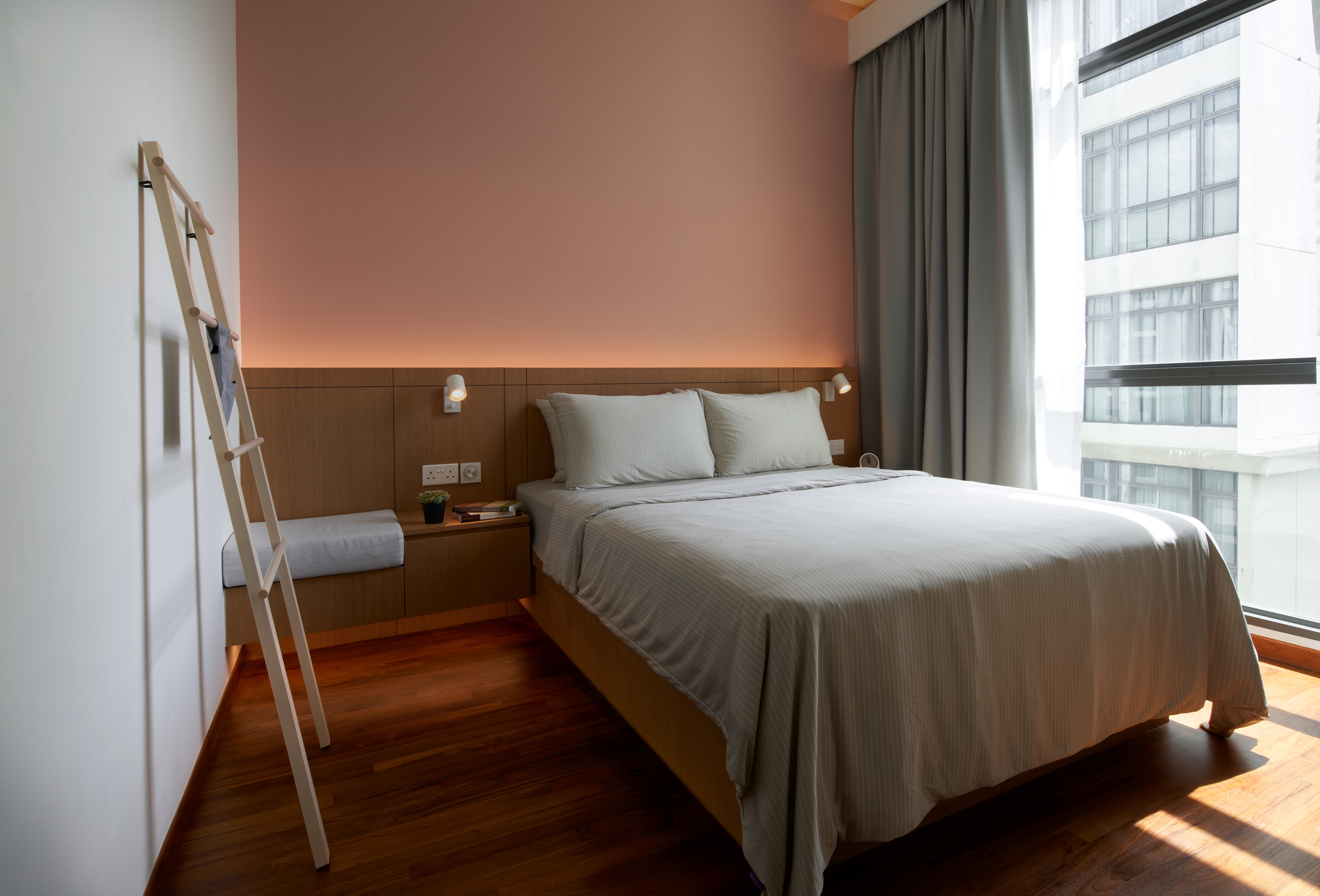 Crafting A Whimsical & Airy Home - Modern bedroom with wooden furniture, large bed with white bedding, warm peach-colored