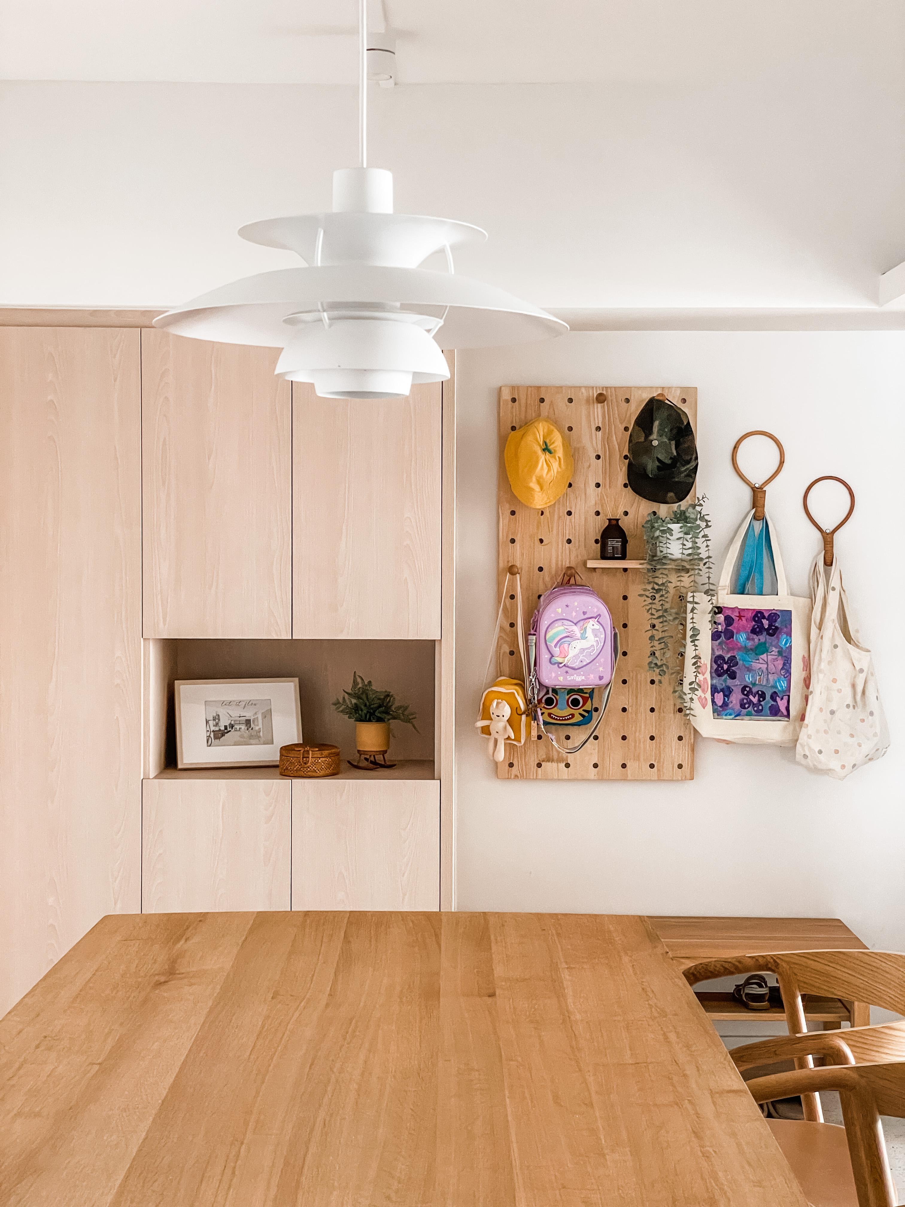 A Welcoming Entryway   - Wooden dining table, minimalist decor, wooden cabinets, white pendant light, yellow hat, purple