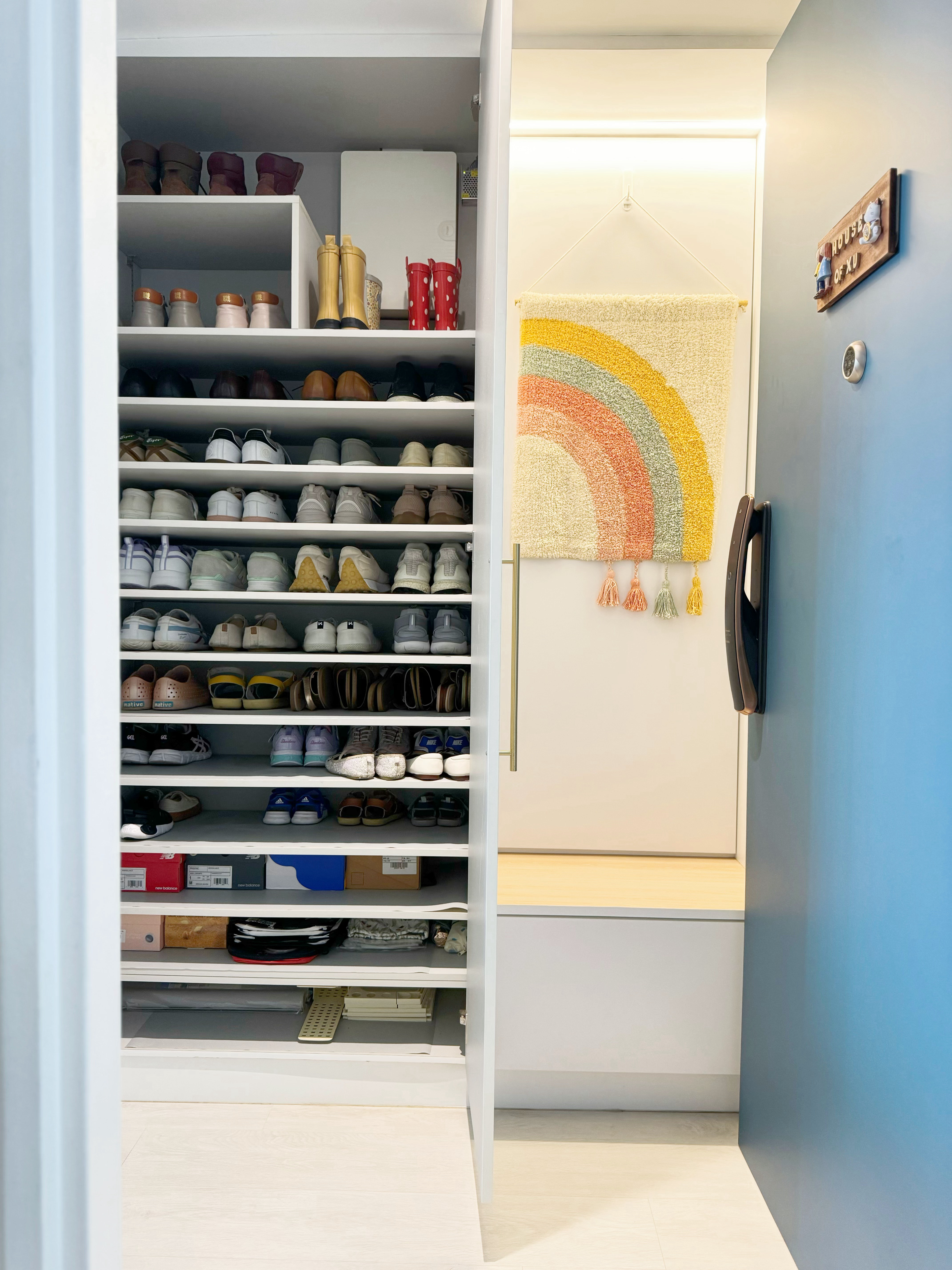 How to Design A Narrow Entryway - Shoe closet with neatly organized shoes, colorful rainbow rug, light blue wall, white door