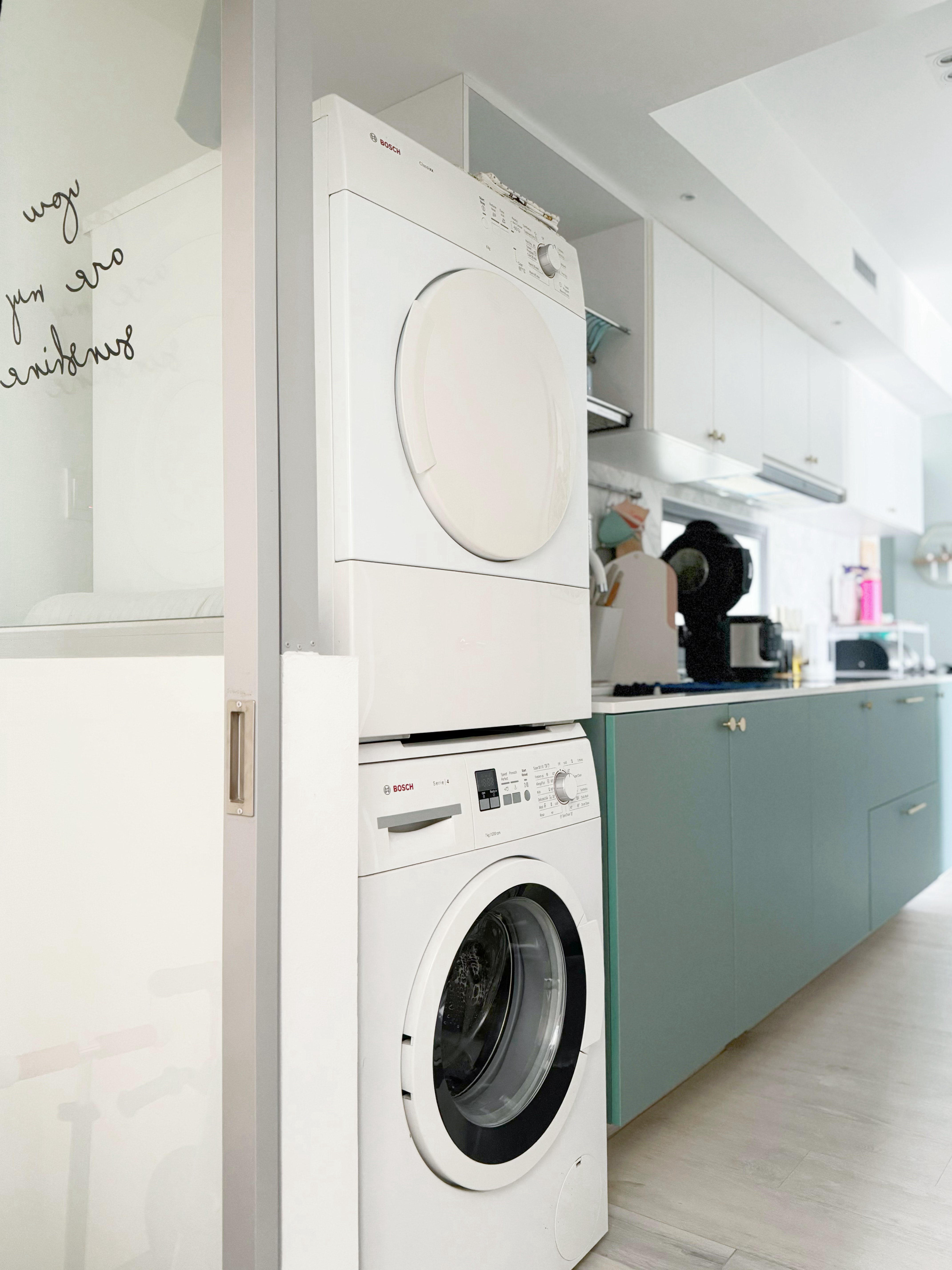 A Small but Efficient Laundry Area - White Bosch washing machine and dryer stacked on top of each other, modern kitchen with