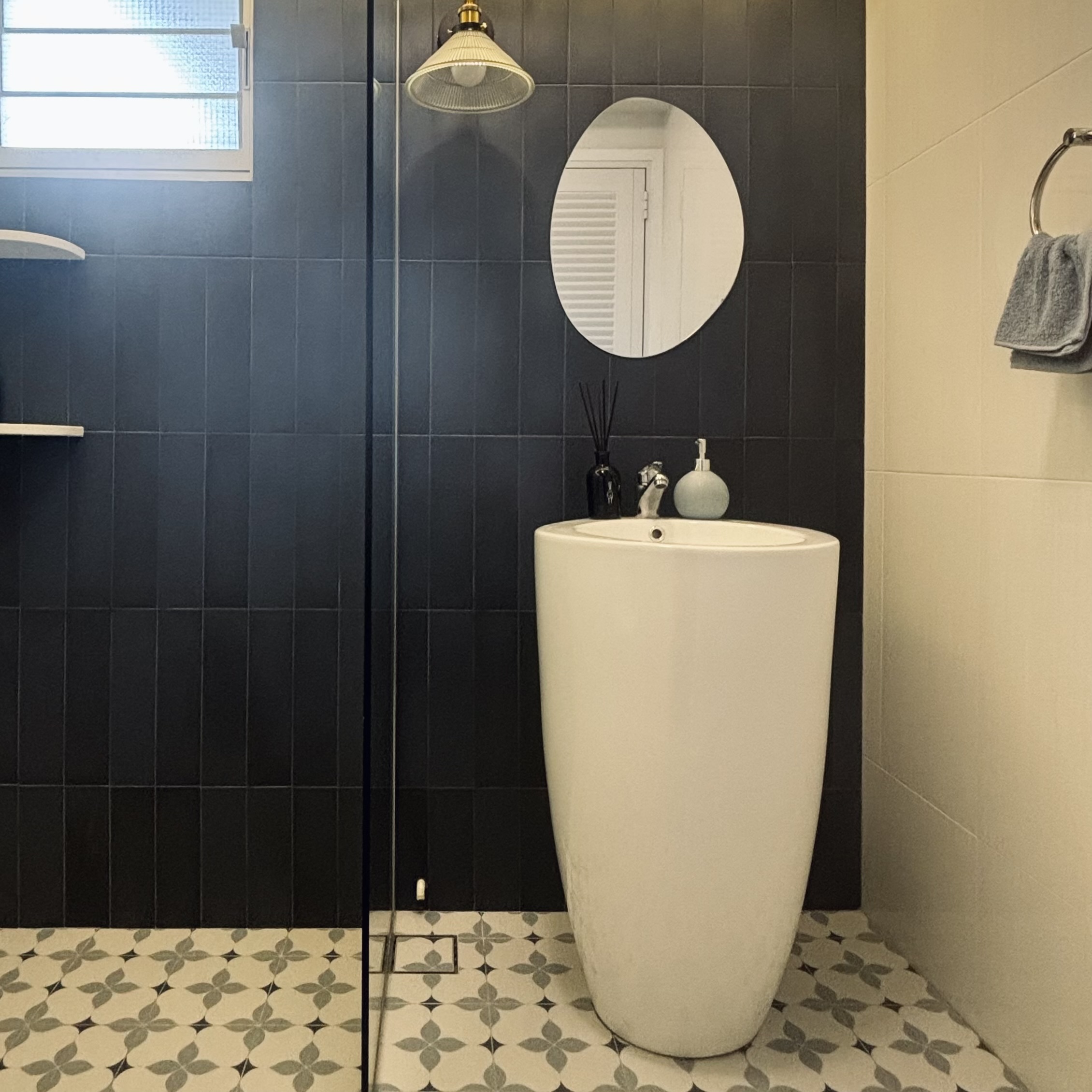Two toilets, two different themes ✨ - Dark gray tiled walls, modern bathroom, white pedestal sink, round mirror, black and