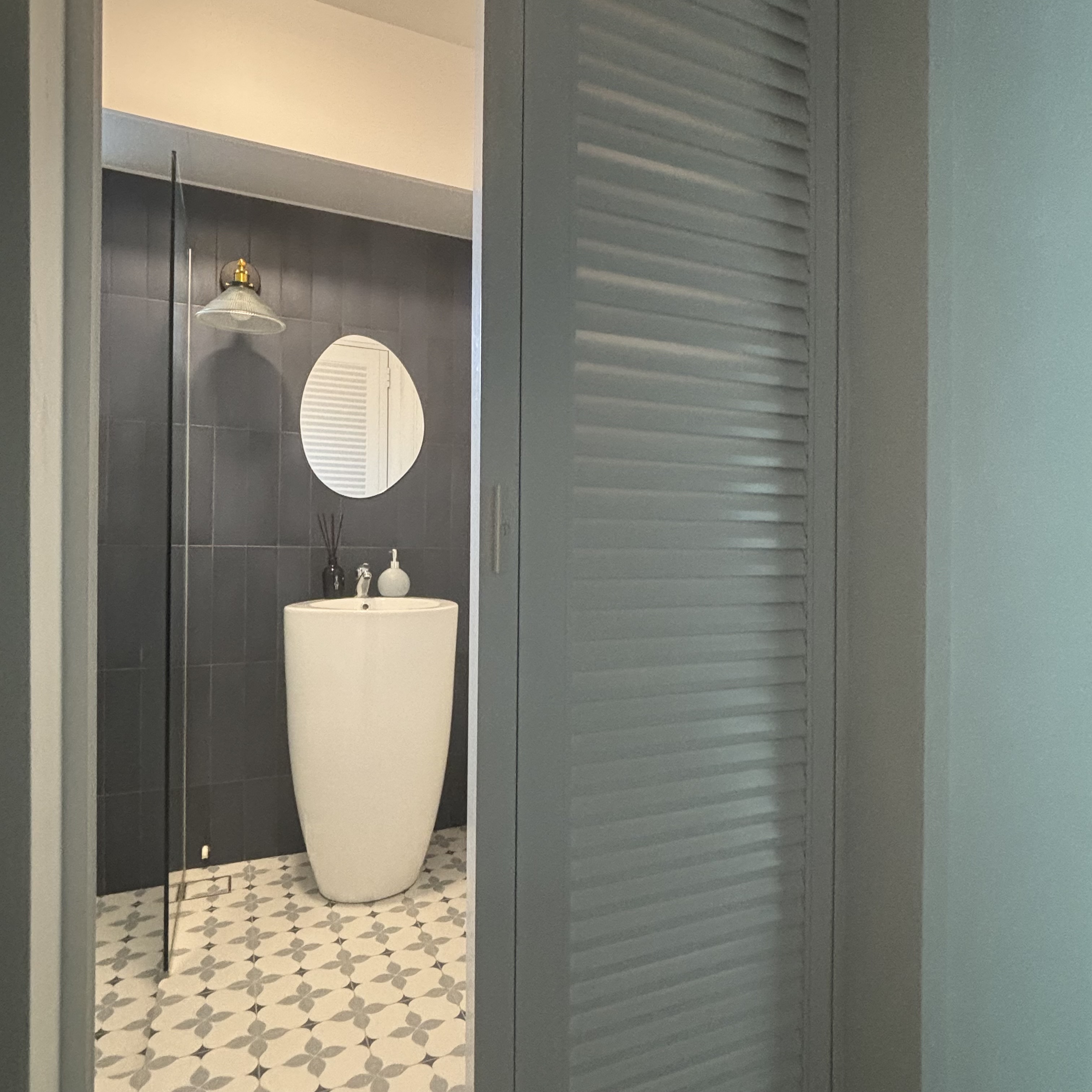 Two toilets, two different themes ✨ - modern bathroom, contemporary design, stylish sink, circular mirror, dark tiles, white