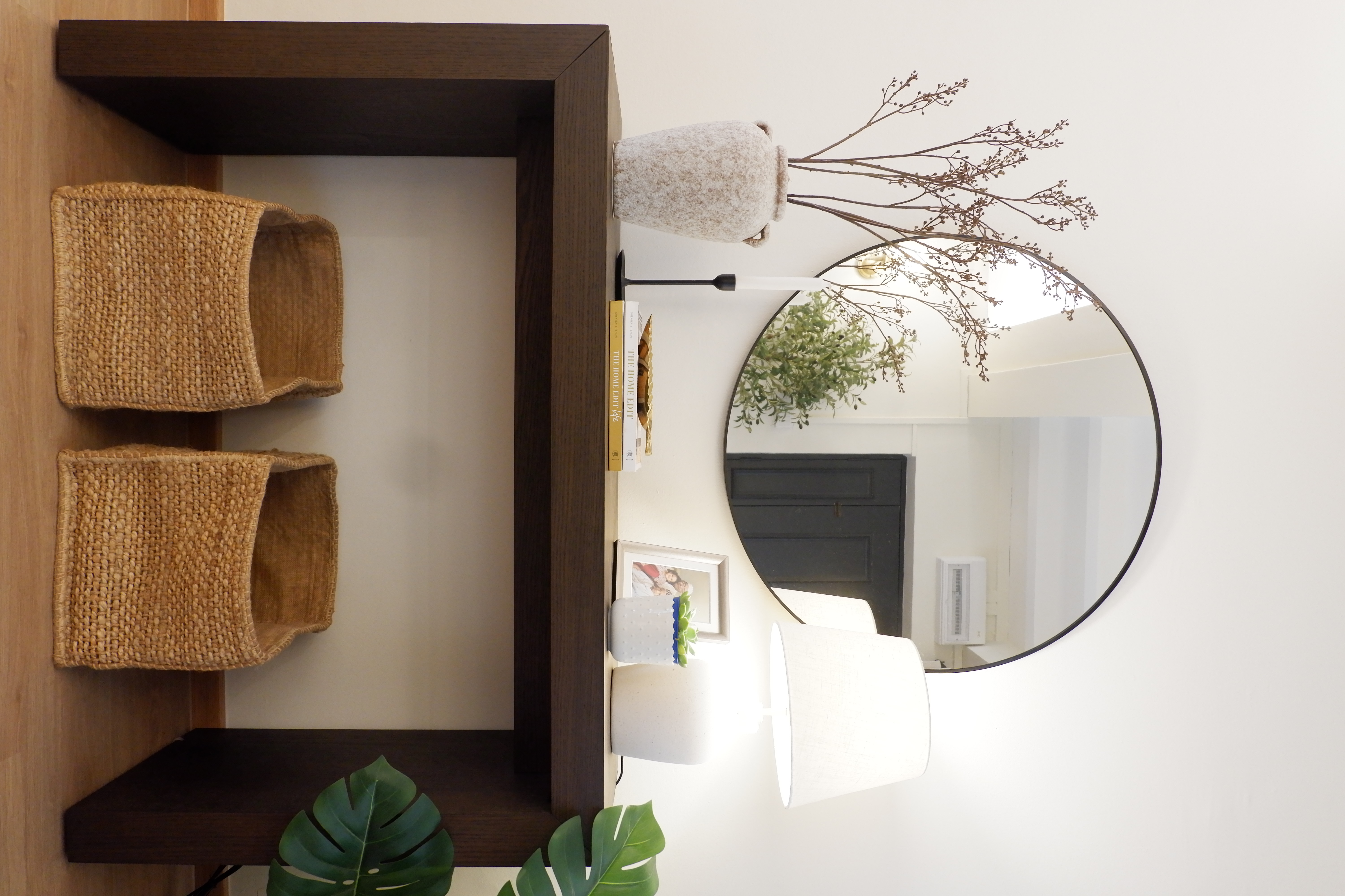 Styling Our Entryway for a Warm Welcome - brown woven shelf, minimalist decor, round mirror, white lamp, green leafy plant