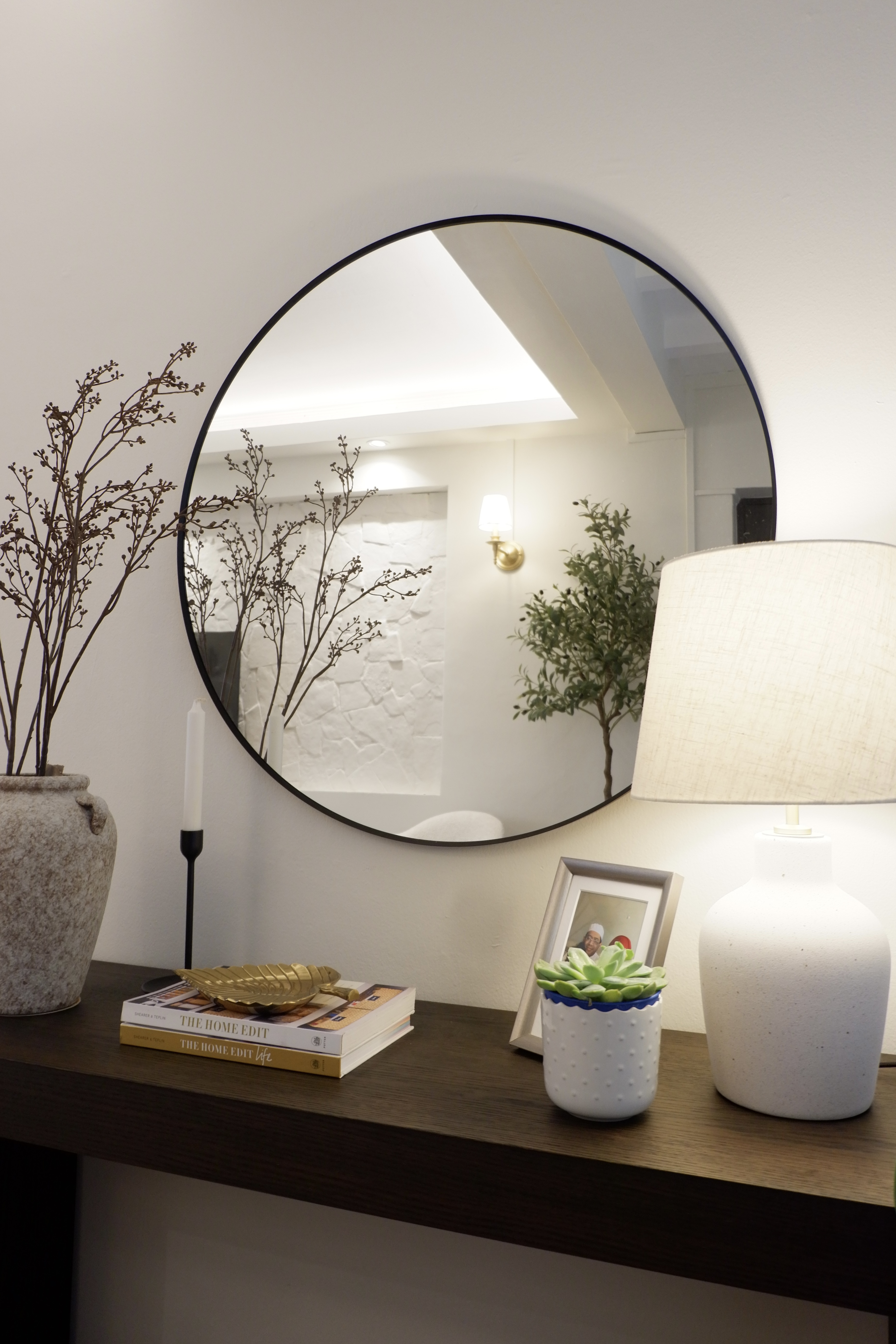 Styling Our Entryway for a Warm Welcome - Round mirror, white wall, minimalist decor, indoor plants, wooden shelf, books
