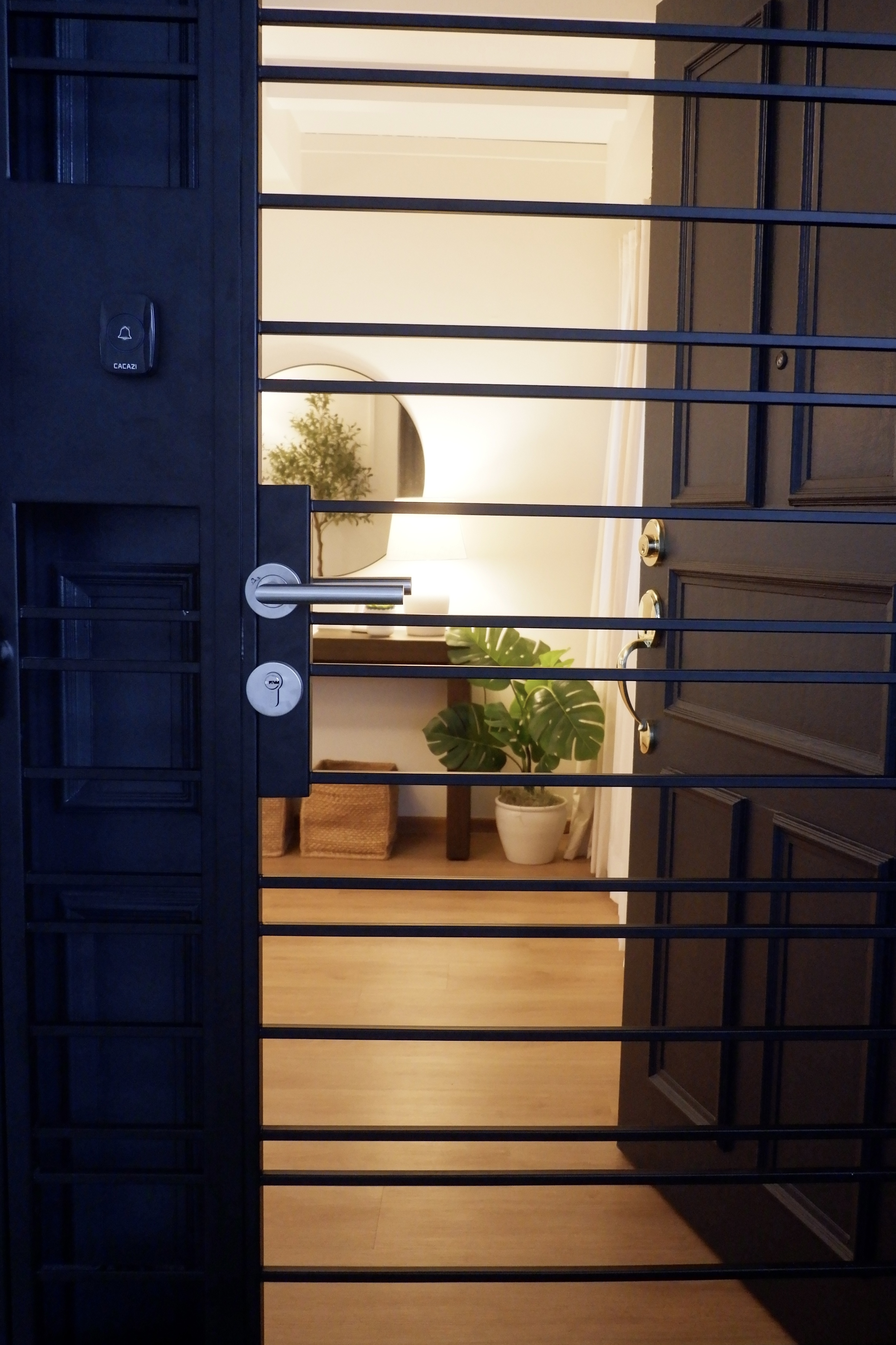Styling Our Entryway for a Warm Welcome - Dark, metal gate, black door, vertical bars, indoor setting, warmly lit room