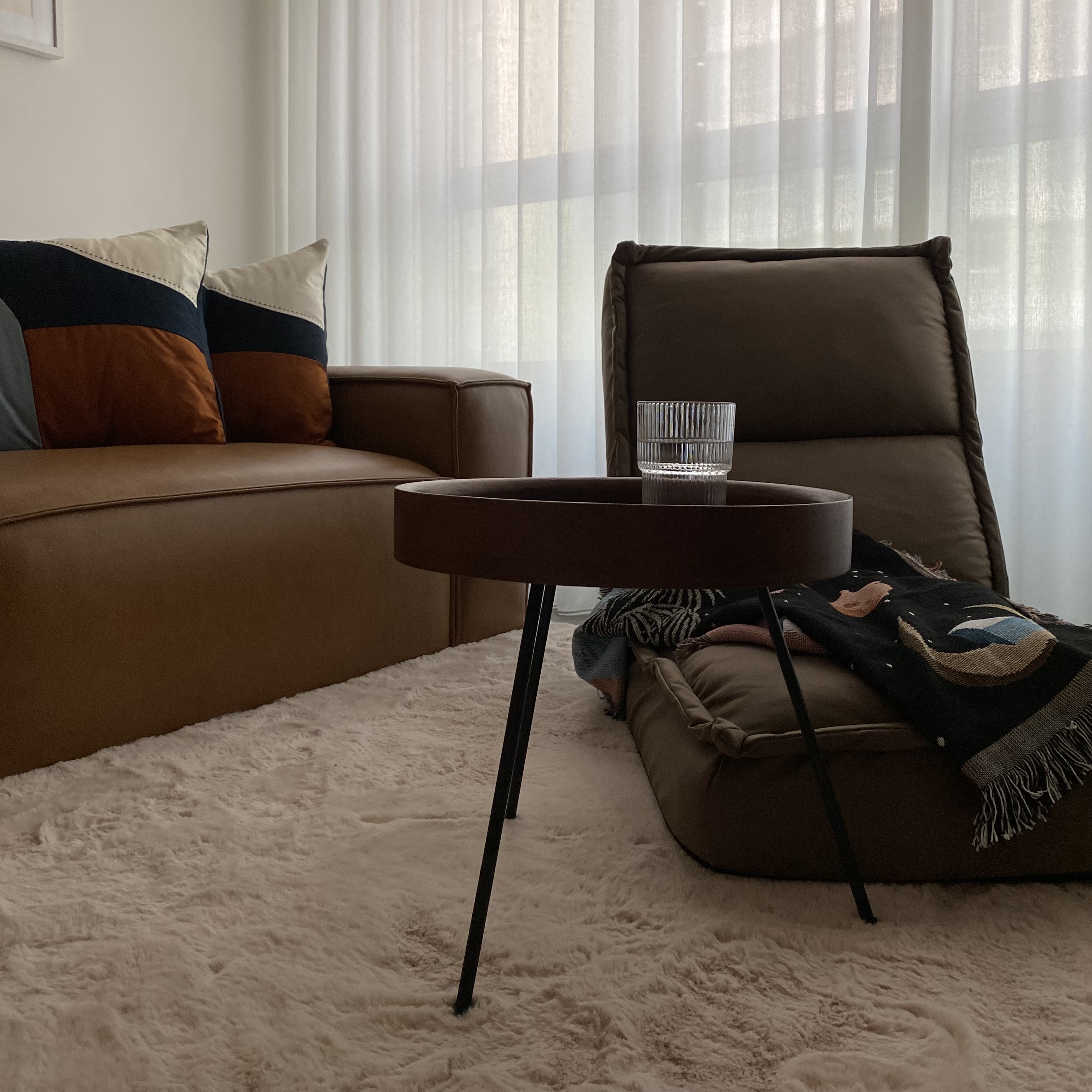 Creating comfortable nooks all around the house! - Brown leather sofa, navy blue and beige pillows, white sheer curtains