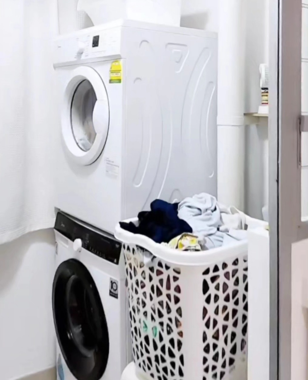 Laundry room of #punggoHField - White laundry room, stacked washer and dryer, pile of clothes, laundry basket, white laundry