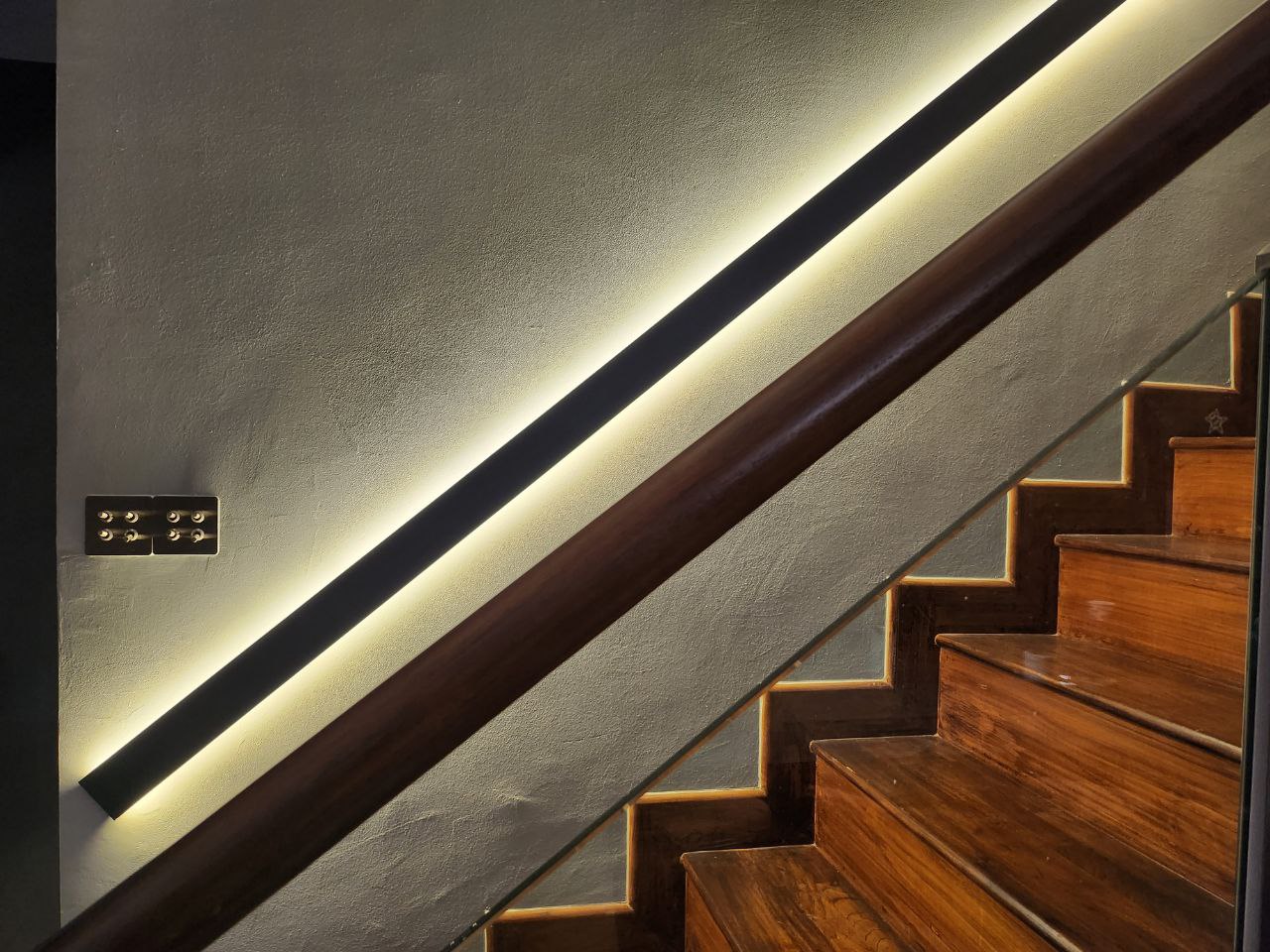 Bright and Airy Modern Home - Modern staircase with sleek wooden steps and glass railing, illuminated by soft, warm LED