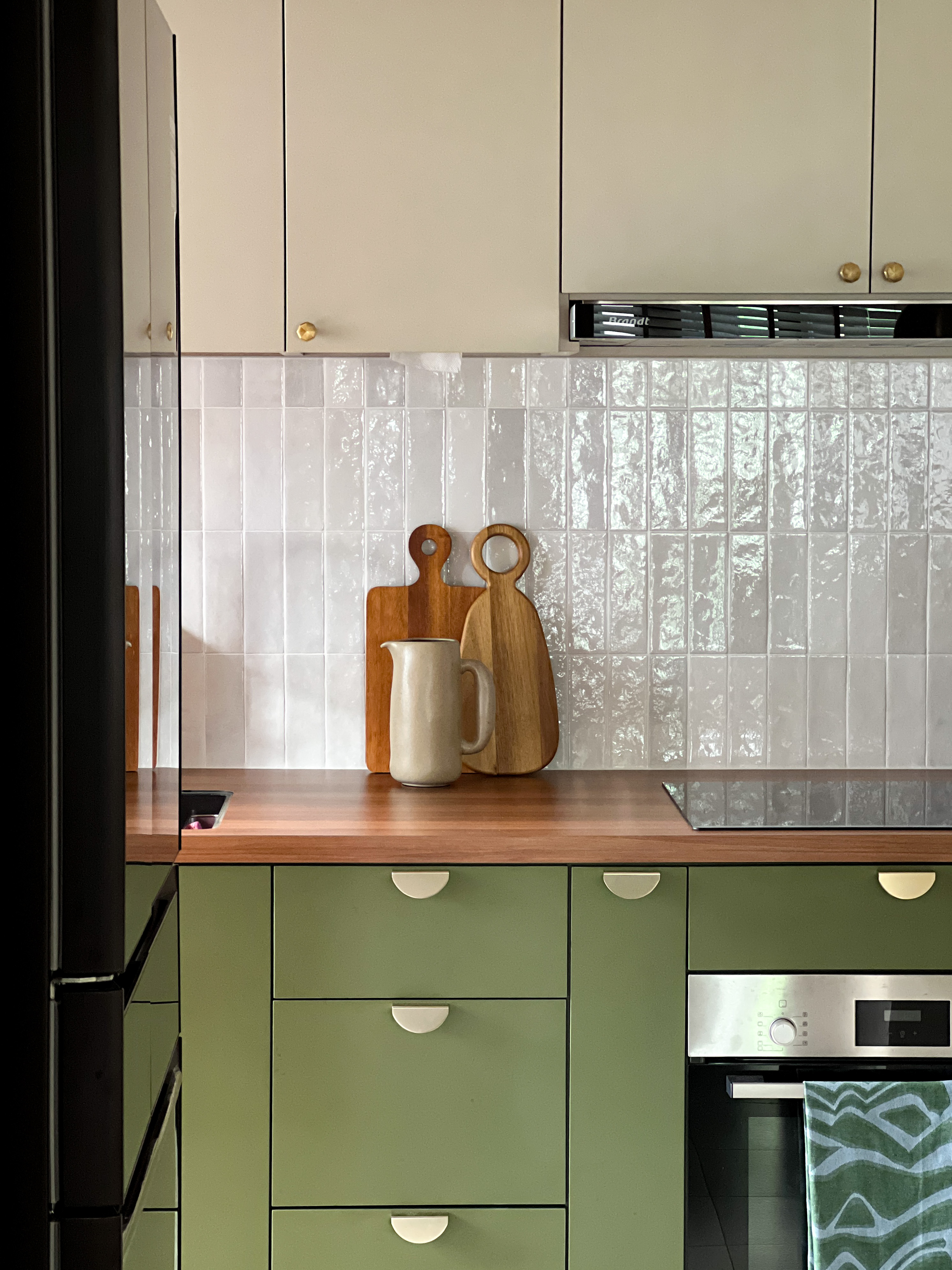 A mix of everything, with a bit of everything.  - White tiled backsplash, wooden countertop, green cabinets, stainless steel
