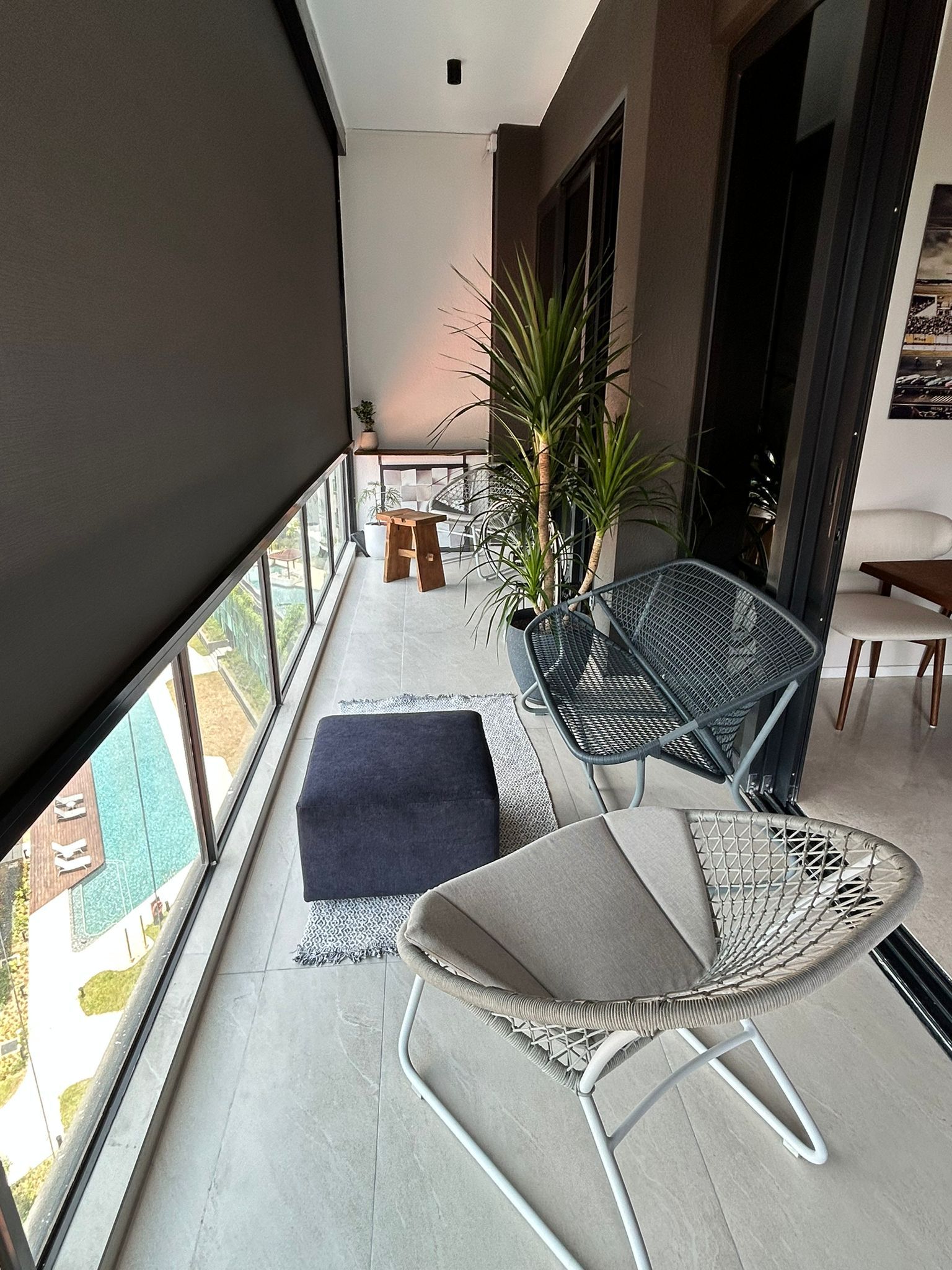 a place to call home finally - Modern balcony with large windows, sleek black roller shade, minimalist furniture